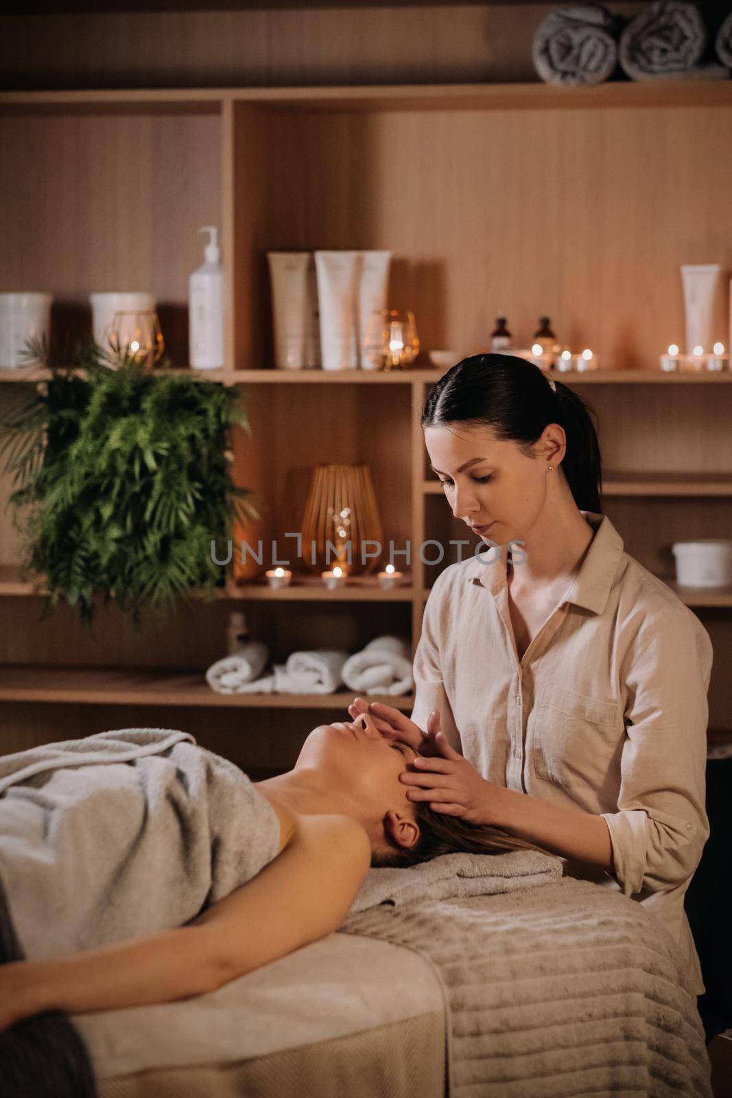 A cosmetologist girl does a facial and neck massage to a girl in the office for skin elasticity.