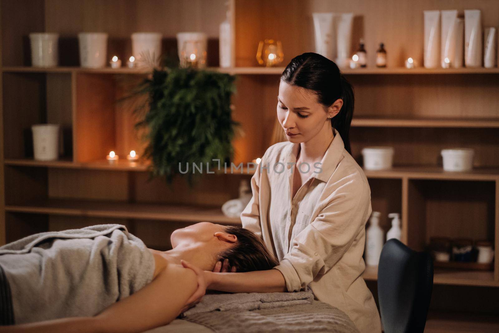 A cosmetologist girl does a facial and neck massage to a girl in the office for skin elasticity.