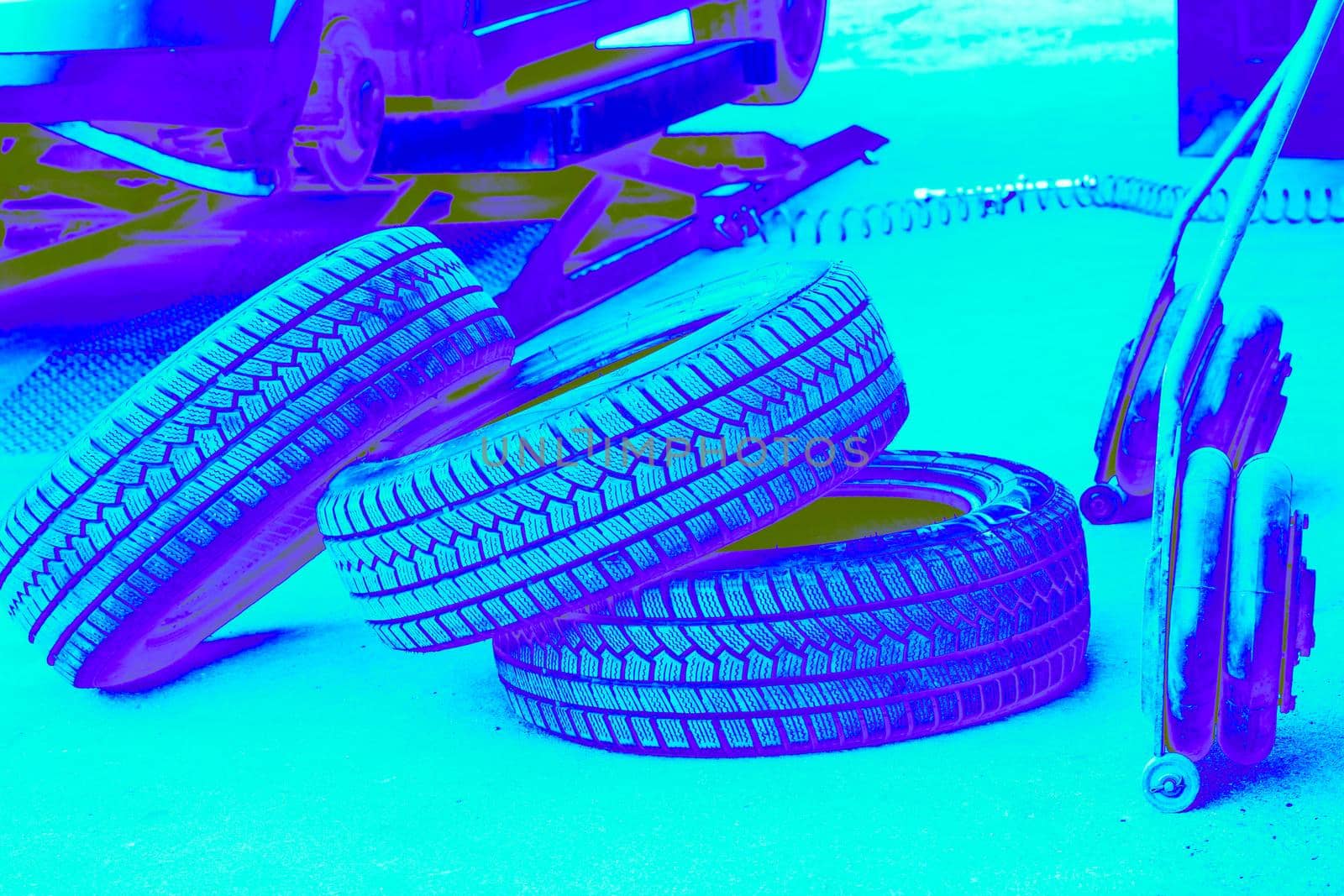 Blue neon replacing a car wheel at a tire station. a rubber covering, typically inflated or surrounding an inflated inner tube, placed around a wheel to form a flexible contact with the road.