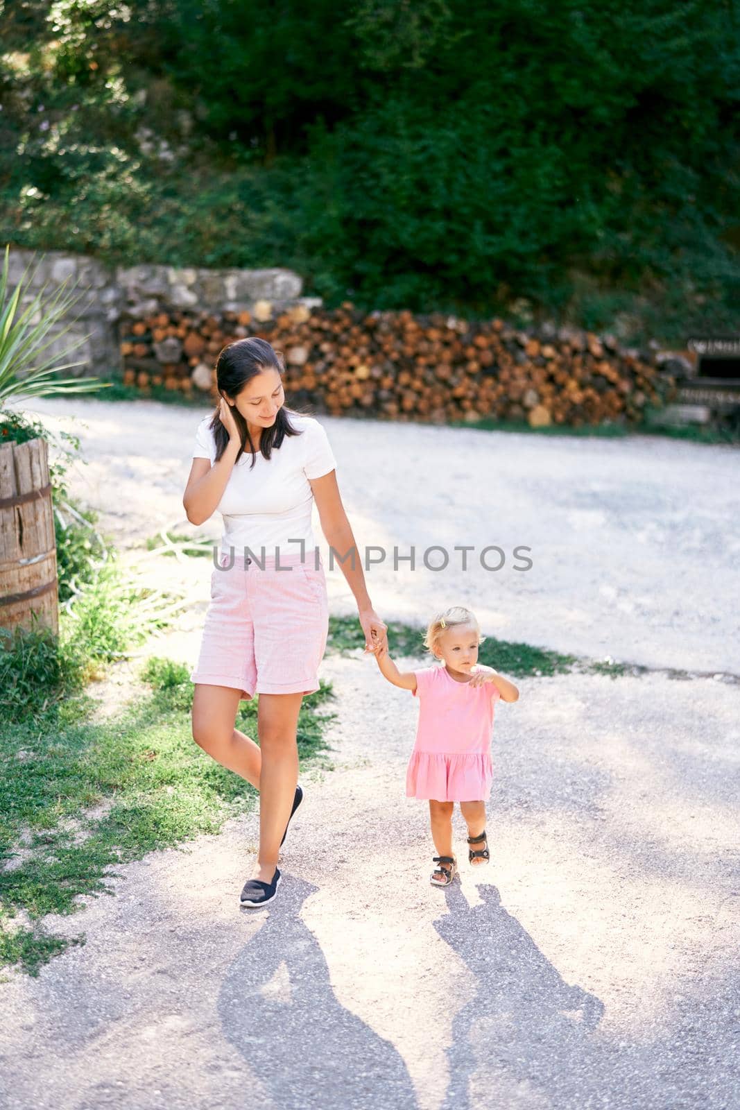 Mom leads the hand of a little girl in the park. High quality photo