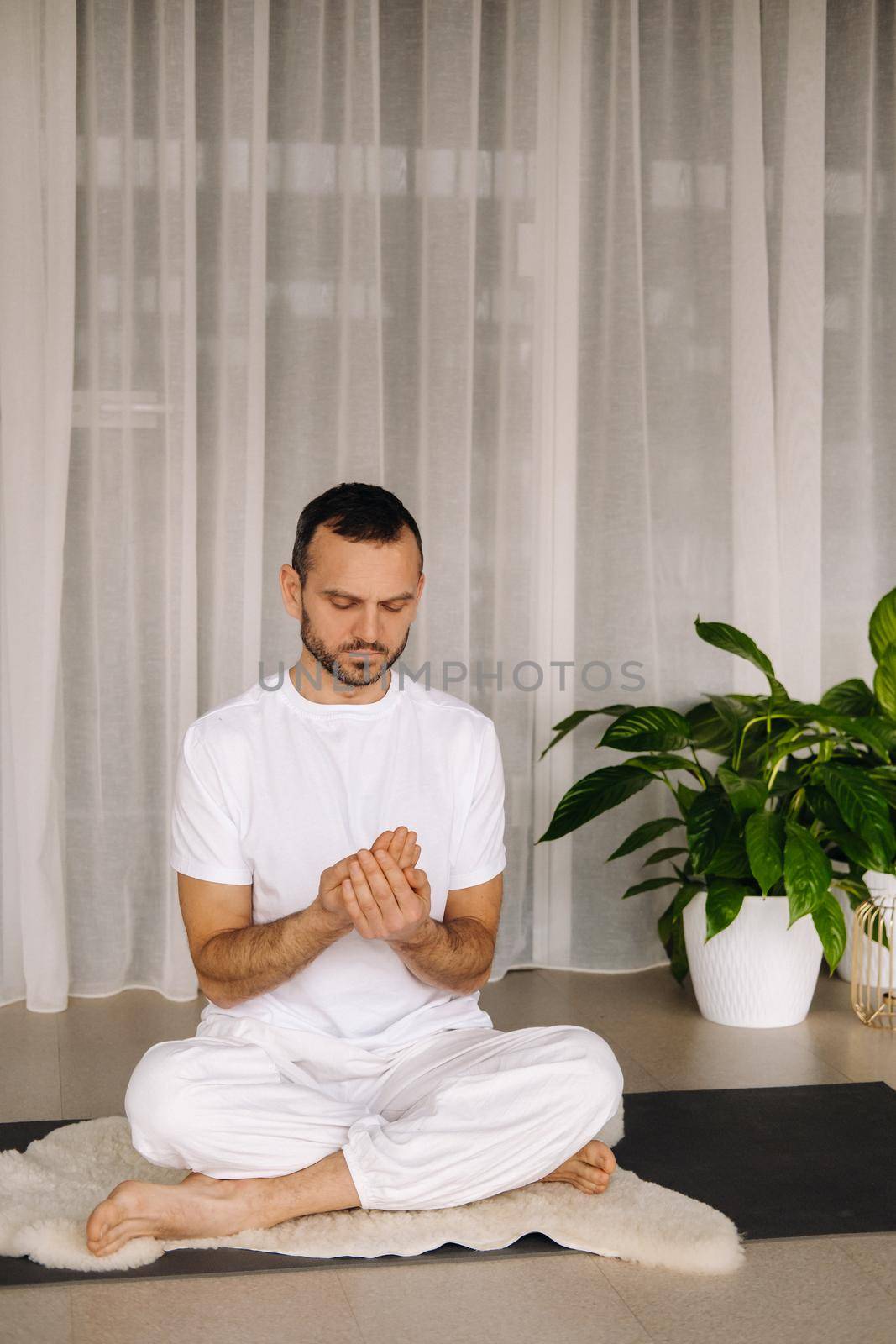 a man in white sportswear is doing yoga with a fitness room. the concept of a healthy lifestyle.