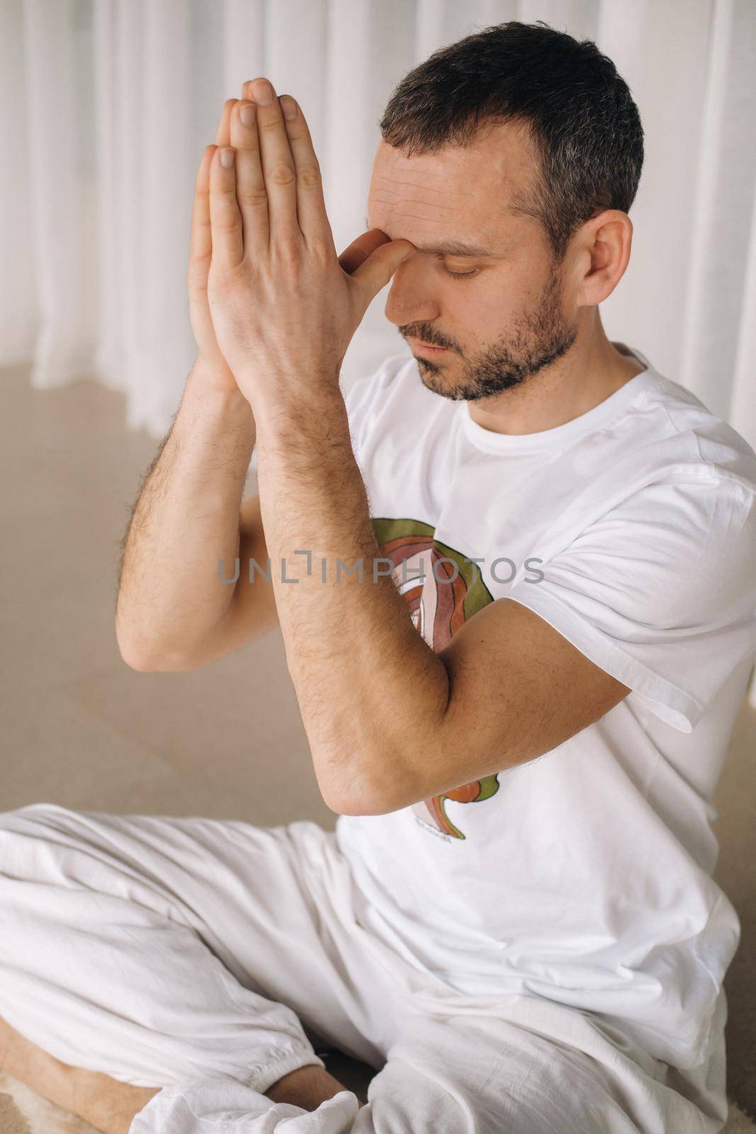 a man in white sportswear is doing yoga with a fitness room. the concept of a healthy lifestyle.