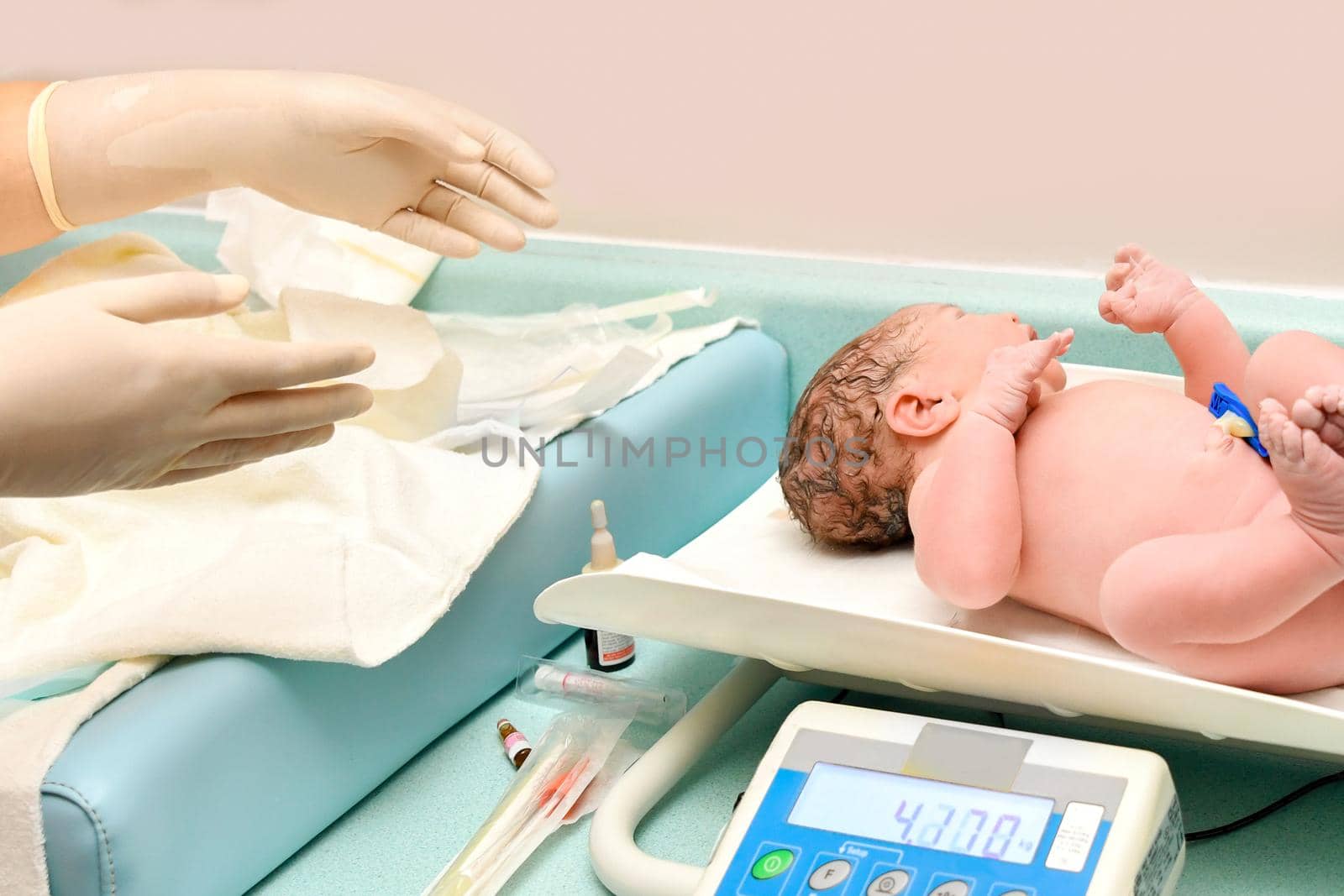 A nurse weighs on the scales a newborn baby