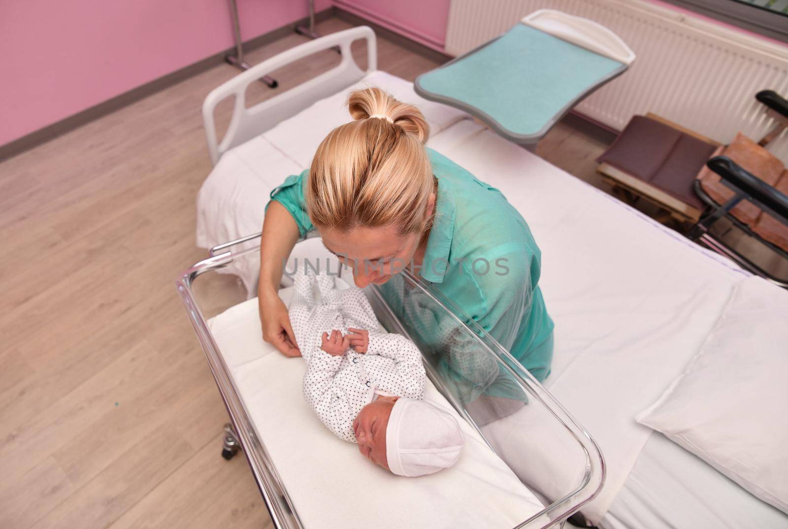 A mother looks at her newborn baby in the hospital ward