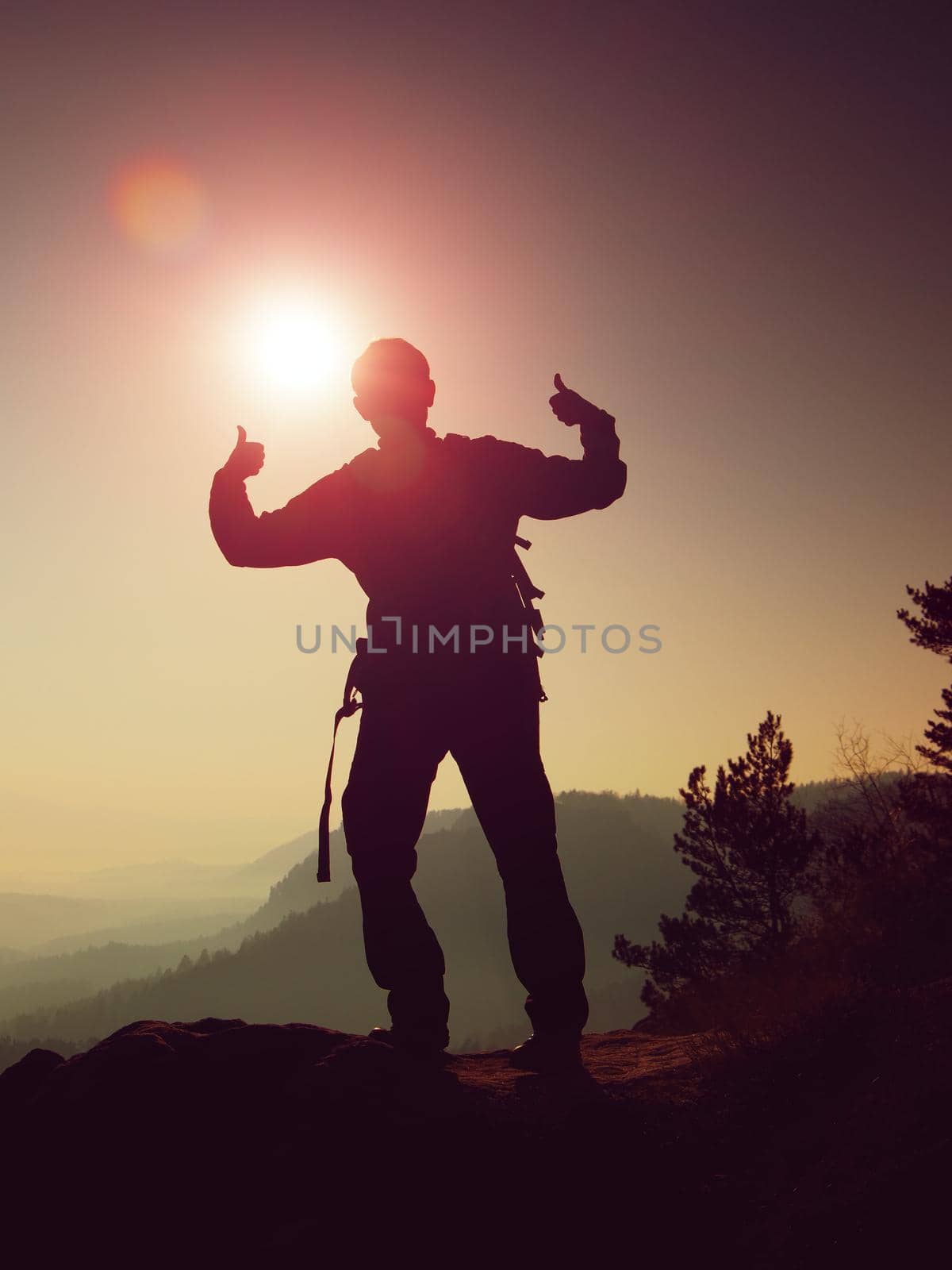 Happy man gesture of triumph. Funny hiker on the peak of sandstone rock in national park Saxony Switzerland watching into camera by rdonar2