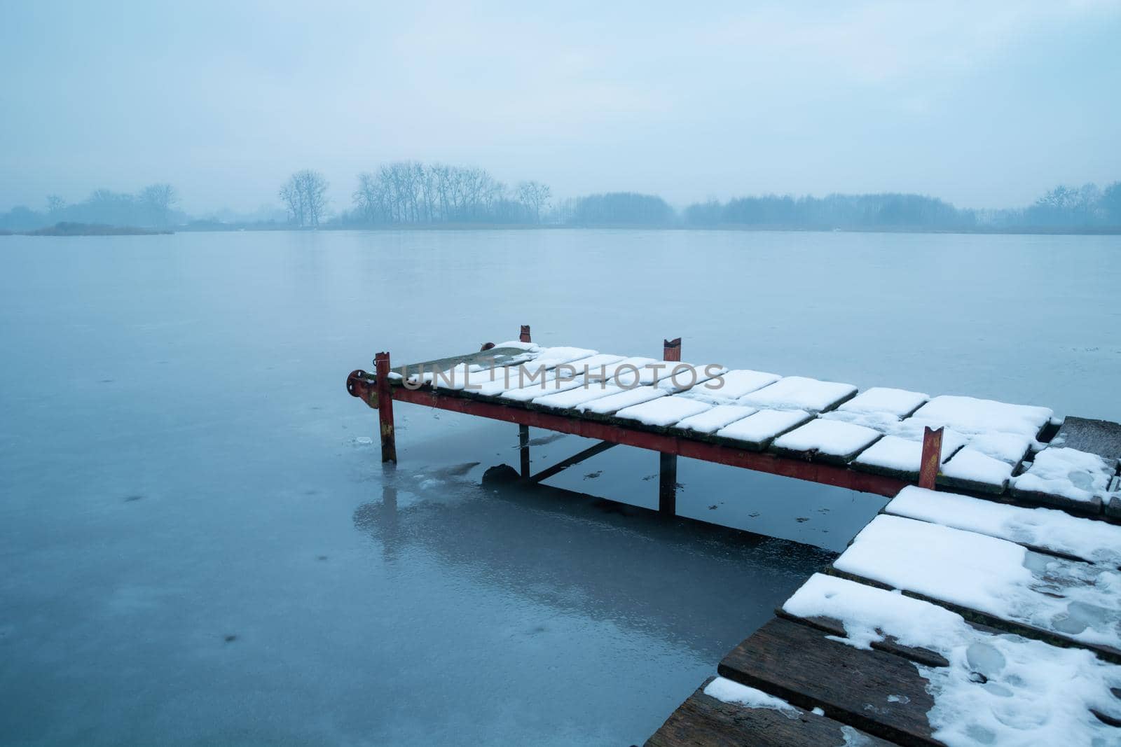 Snow on a pier on a frozen lake, winter view