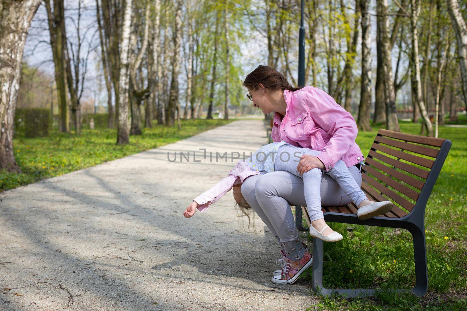Relaxing and having fun, moms with baby in city park. A caregiver holds her baby on her lap on a sunny day.