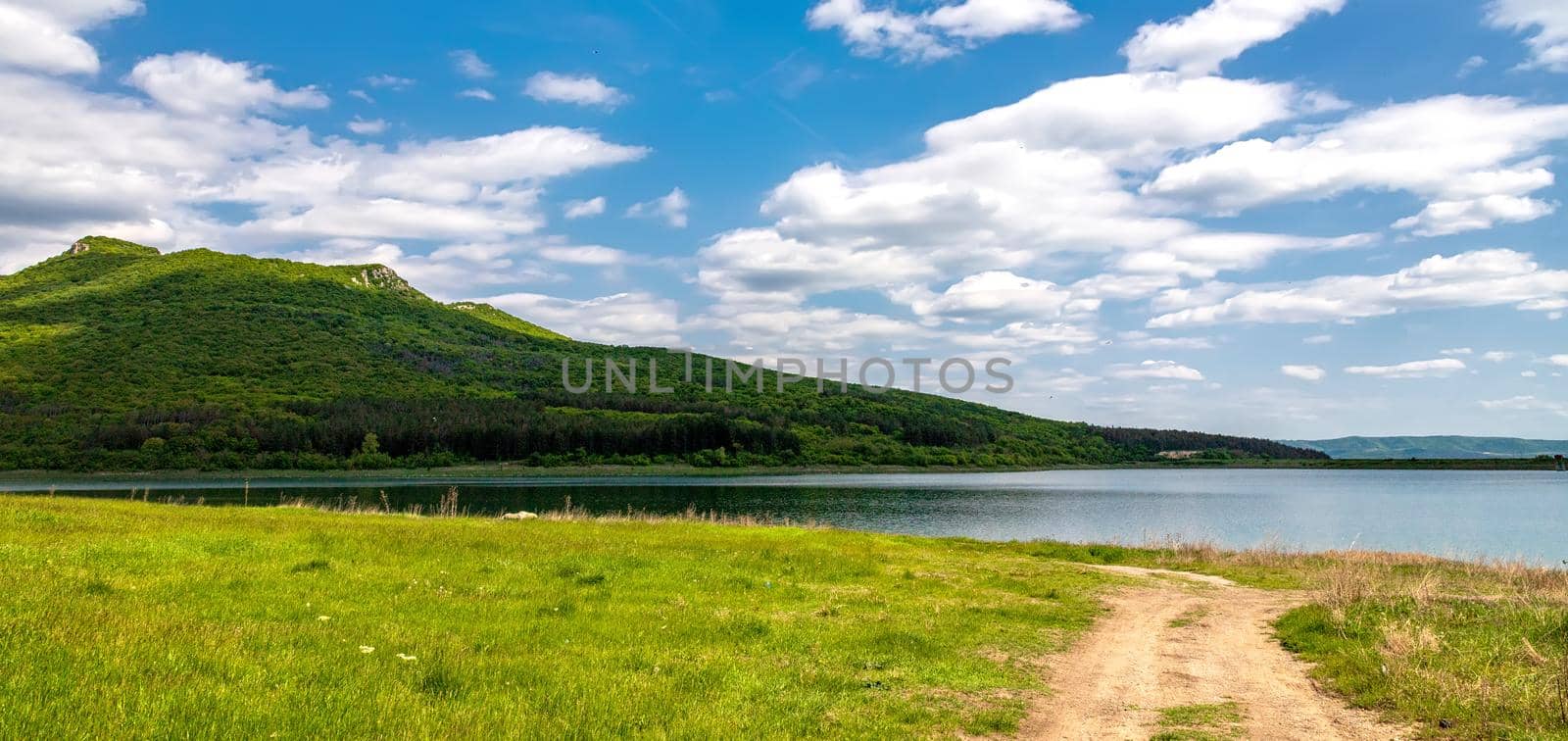 Panoramic view of a lake among hills and country road by EdVal