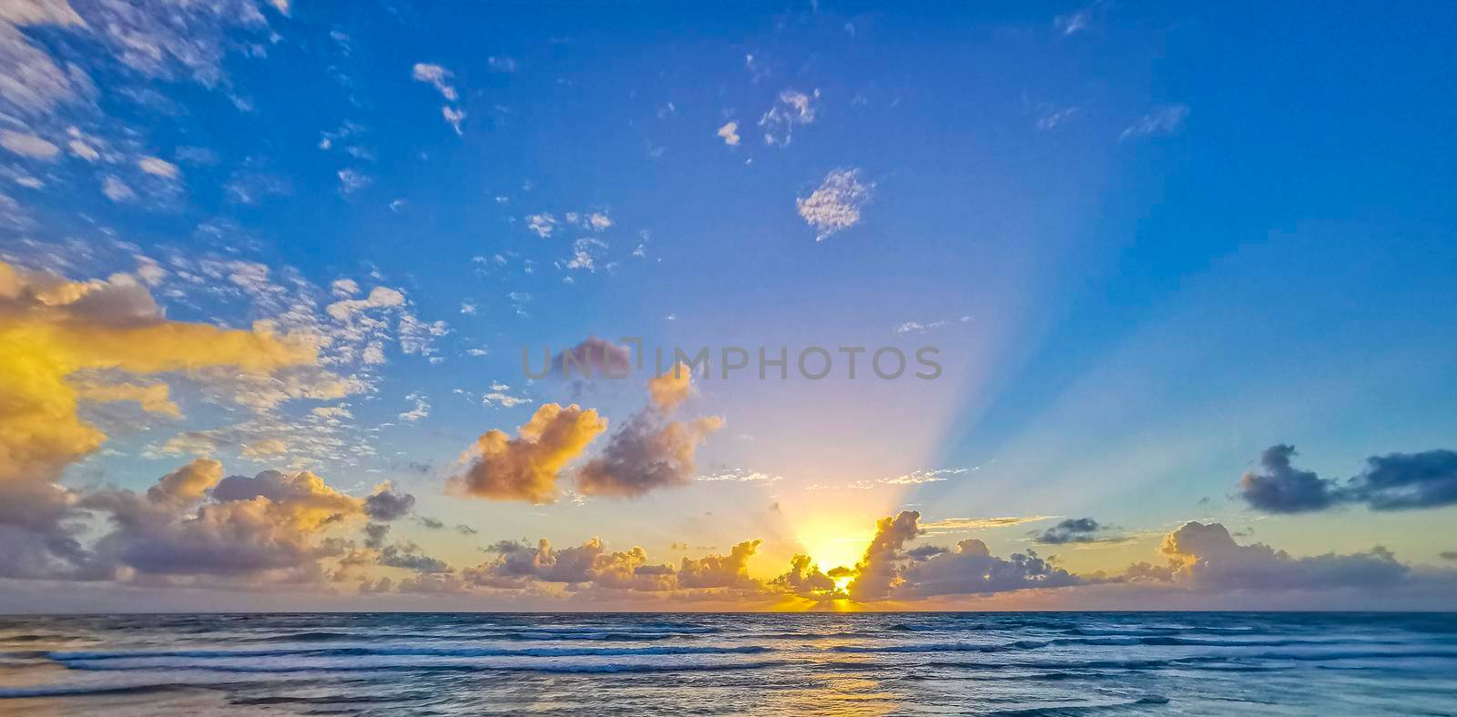 Amazing beautiful golden yellow colorful sunrise sunset with sunbeams at tropical beach with panorama view in Tulum Quintana Roo Mexico.