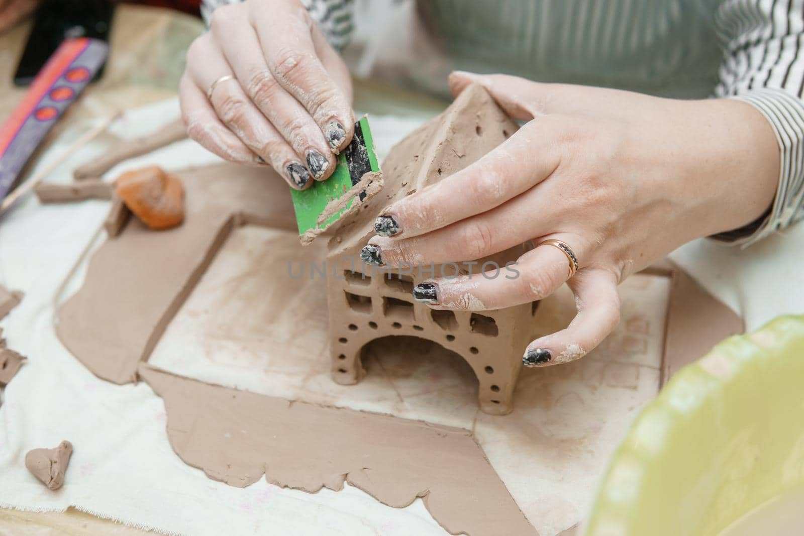 Women's hands knead clay, drawing elements of the product. Production of ceramic products at the master class on ceramics. Close-up.