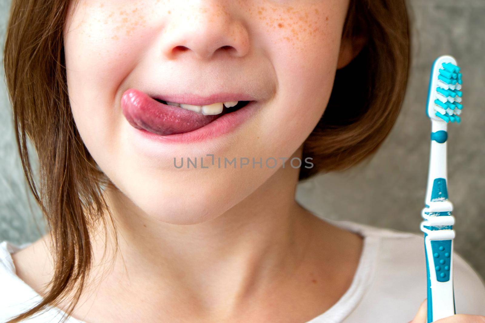 Oral hygiene, healthy teeth and care. Girl brushing teeth with toothbrush and looking in mirror in bathroom interior in the morning, closeup, empty space. High quality photo