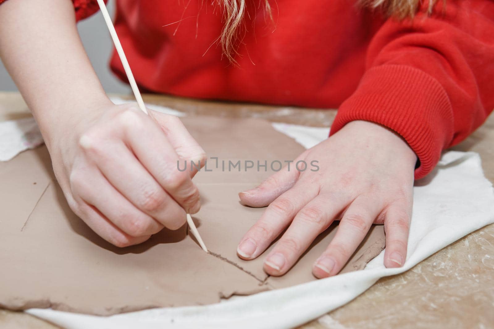 Women's hands knead clay, drawing elements of the product. Production of ceramic products at the master class on ceramics. Close-up. Making a candlestick in the form of a house. Christmas ceramic candle holder.