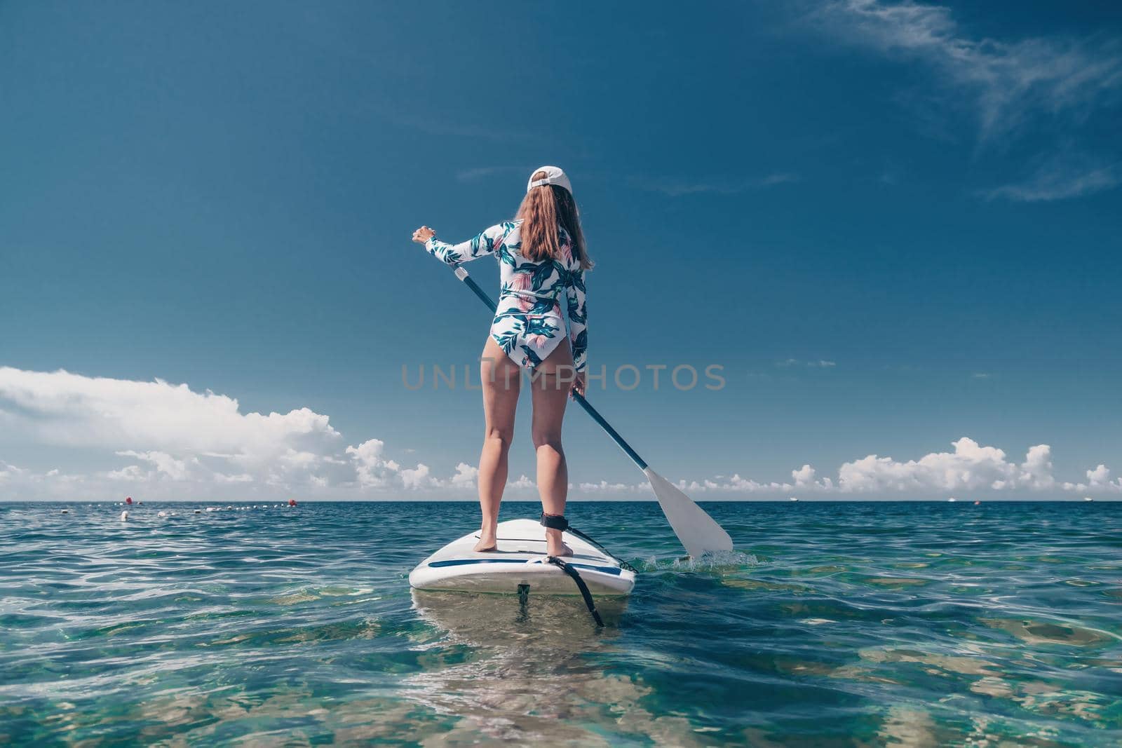 SUP Stand up paddle board. Young woman sailing on beautiful calm sea with crystal clear water. The concept of an summer holidays vacation travel, relax, active and healthy life in harmony with nature