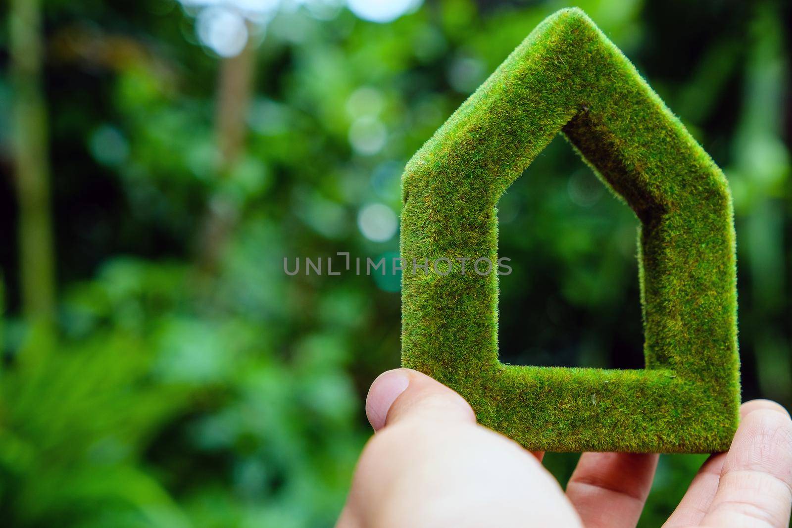 hand holding eco house icon in nature by ponsulak