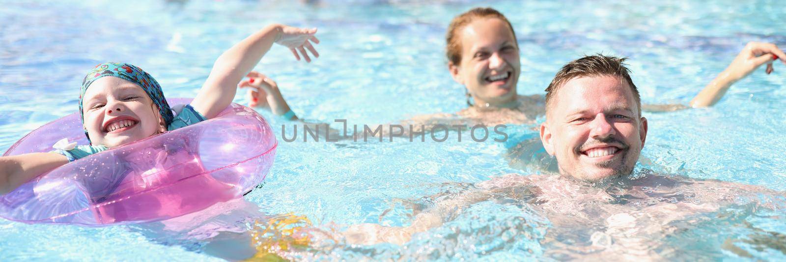 Portrait of mother father and daughter swimming in pool on summer holiday. Happy parent and kid on resort. Summer, childhood, parenthood, leisure concept