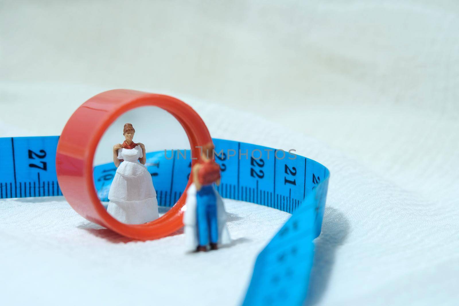 Women miniature people standing above measuring tape to fix her wedding dress. Image photo