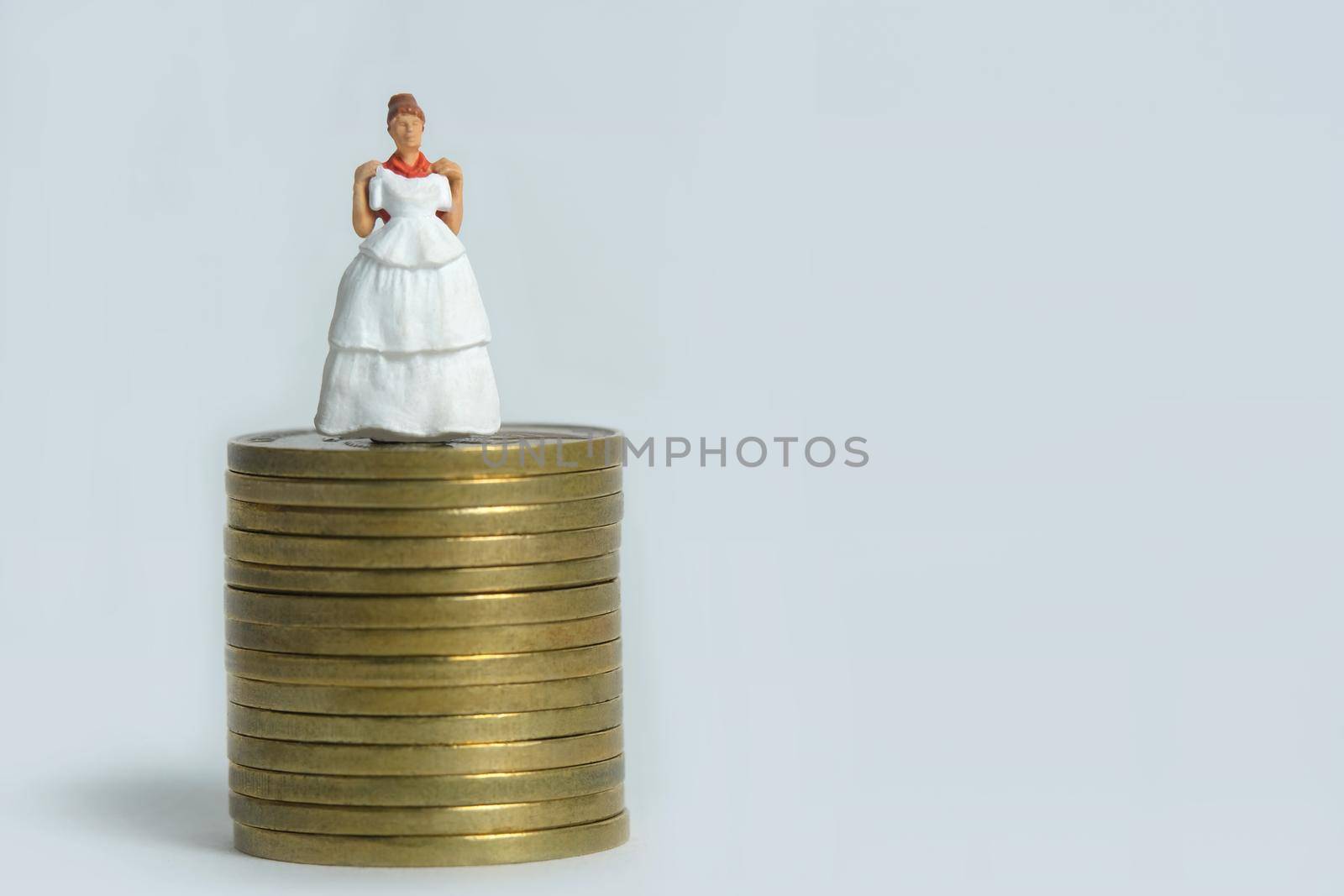 Wedding dress budget for bride, miniature people illustration concept. Woman standing above coin money stack. Image photo by Macrostud