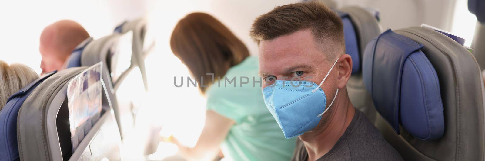 Portrait of couple flying on airplane, reading magazine to kill time. Fly high in sky, wear face masks on flight. Airplane, coronavirus, pandemic concept