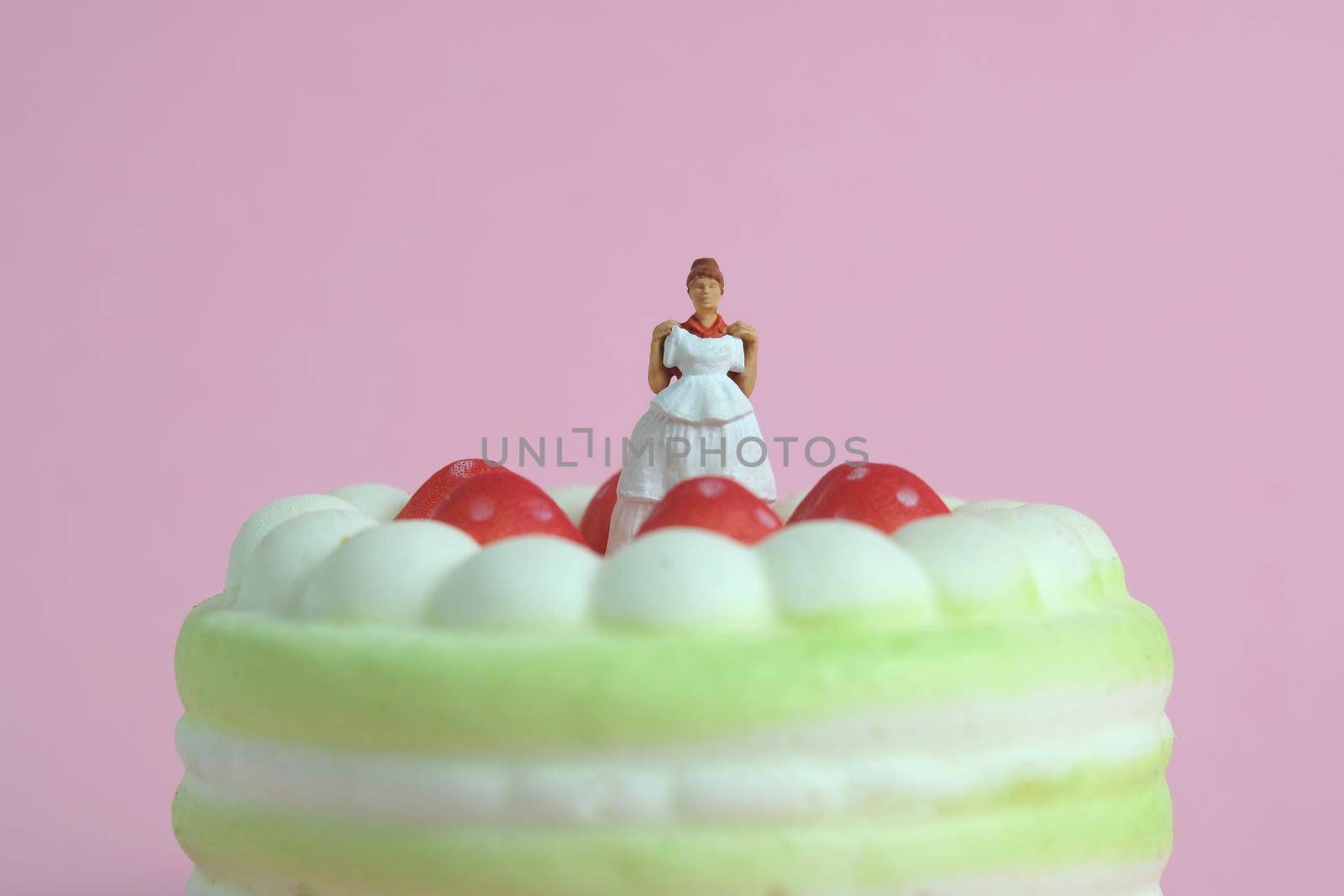 Woman dieting from cake before wedding day concept. Miniature people toys photography, girl holding wedding dress. Image photo by Macrostud