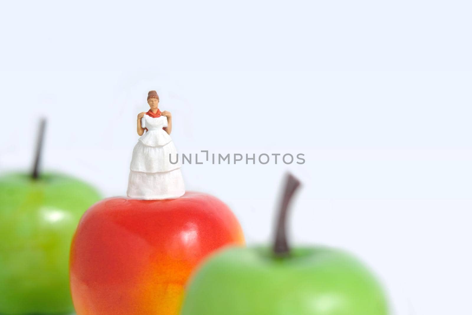 Diet plan before wedding or marriage day concept. Woman standing above apple with trying wedding dress. Miniature people, toys photography.