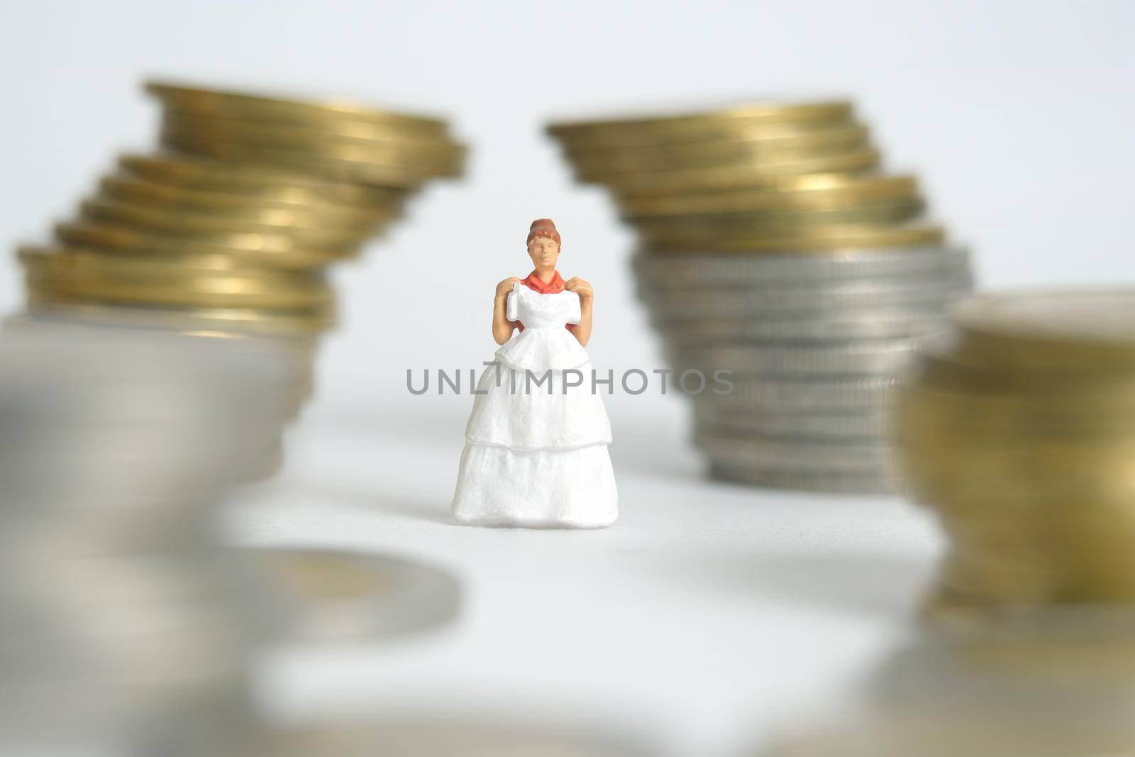 Wedding dress budget for bride, miniature people illustration concept. Woman standing between coin money stack. Image photo by Macrostud