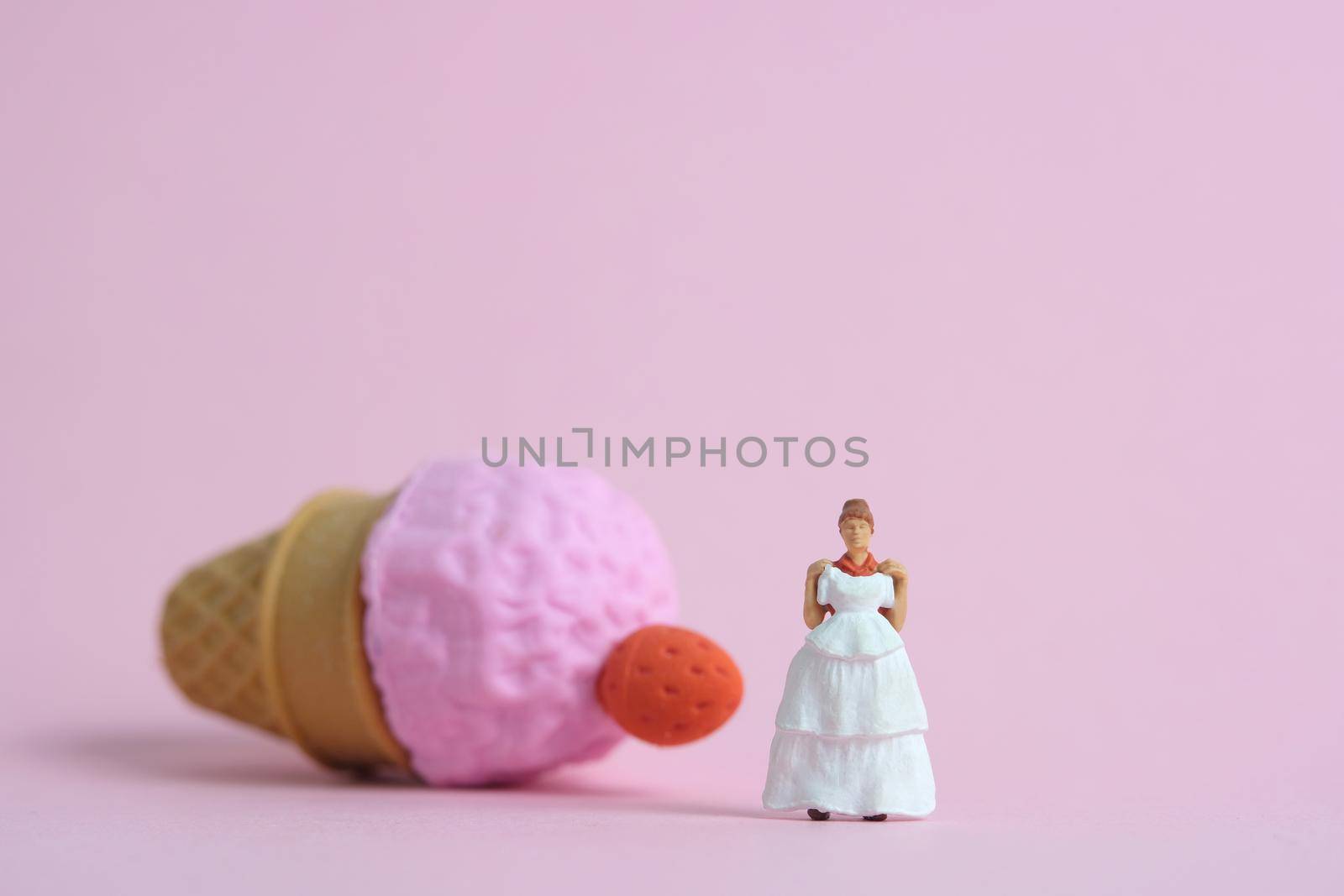 Woman dieting from ice cream and fat before wedding day concept. Miniature people toys photography, girl holding wedding dress. Image photo by Macrostud