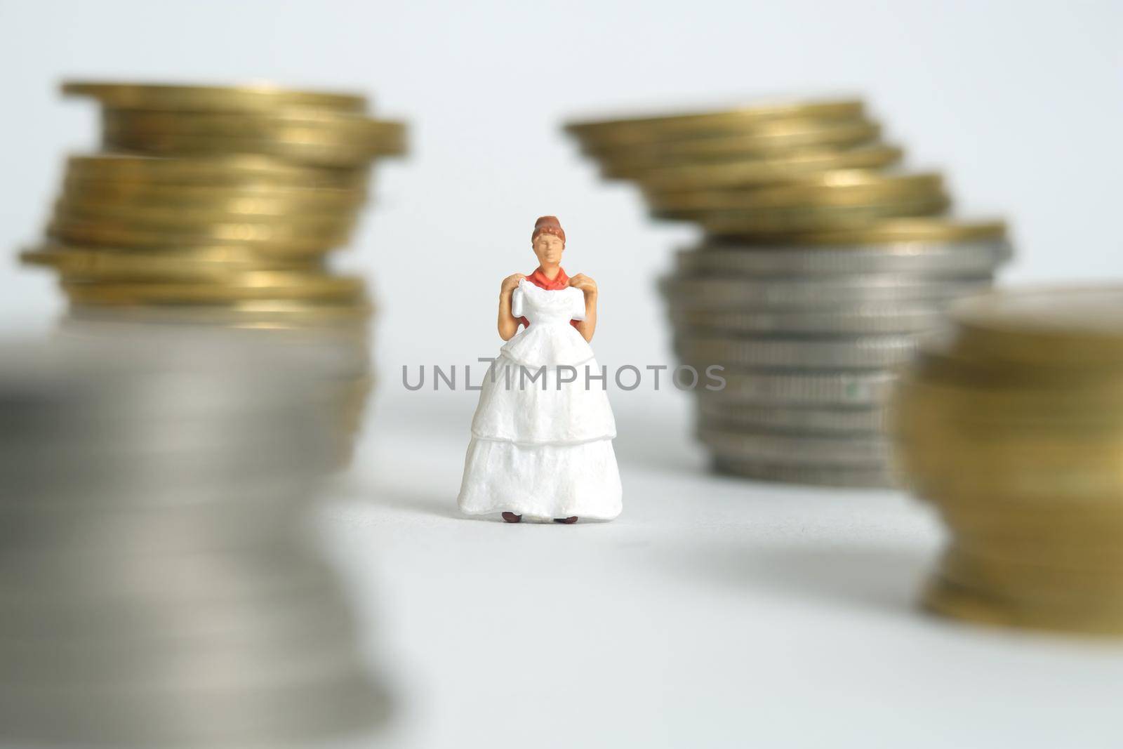 Wedding dress budget for bride, miniature people illustration concept. Woman standing between coin money stack. Image photo