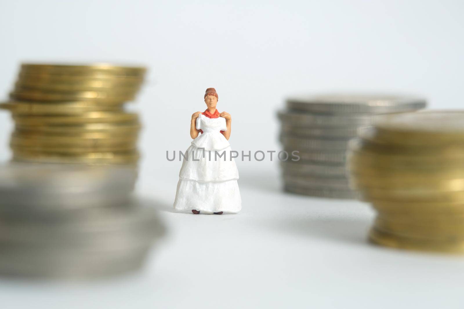 Wedding dress budget for bride, miniature people illustration concept. Woman standing between coin money stack. Image photo by Macrostud
