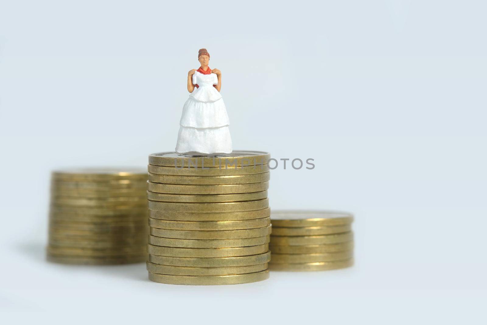 Wedding dress budget for bride, miniature people illustration concept. Woman standing above coin money stack. Image photo