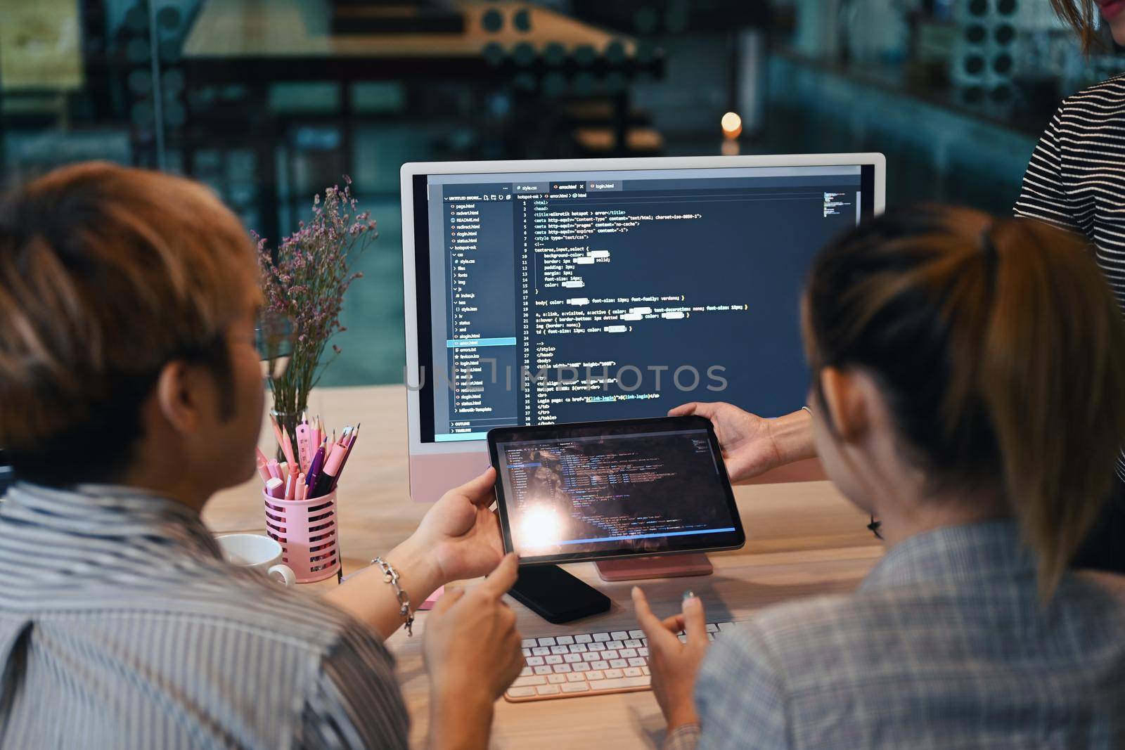 Back view of IT developer team programming code on computer screen and brainstorming for new project at modern office by prathanchorruangsak