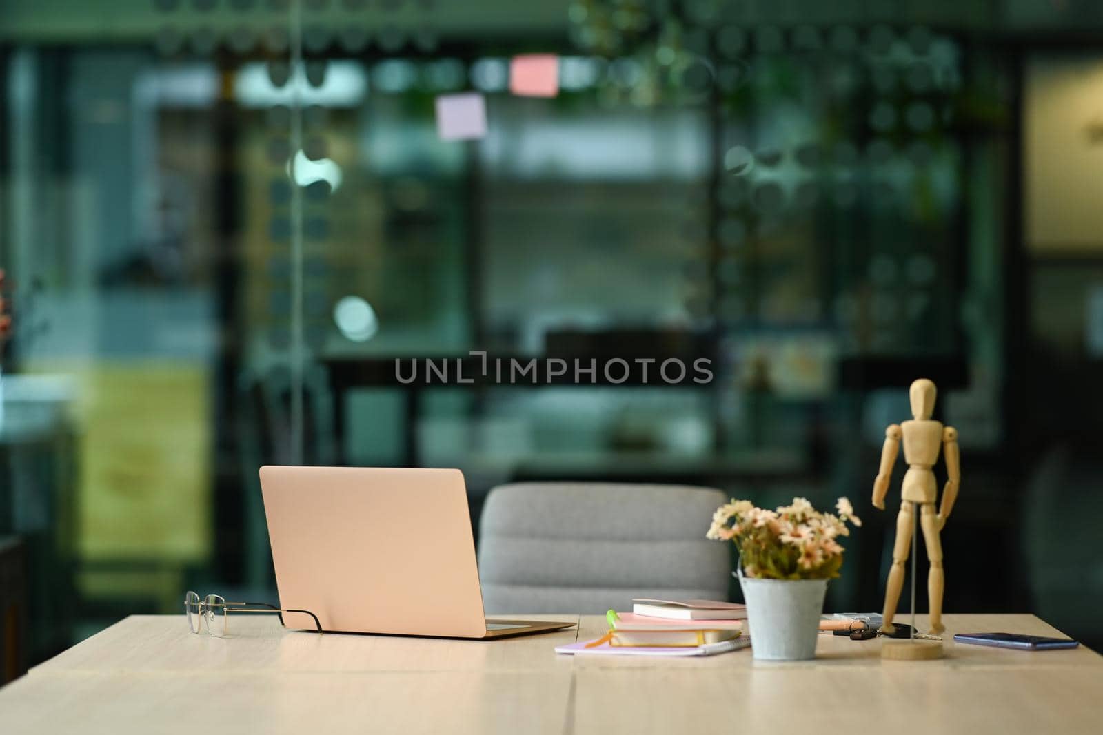 White office desk with laptop computer, glasses, notebooks and flower pot.