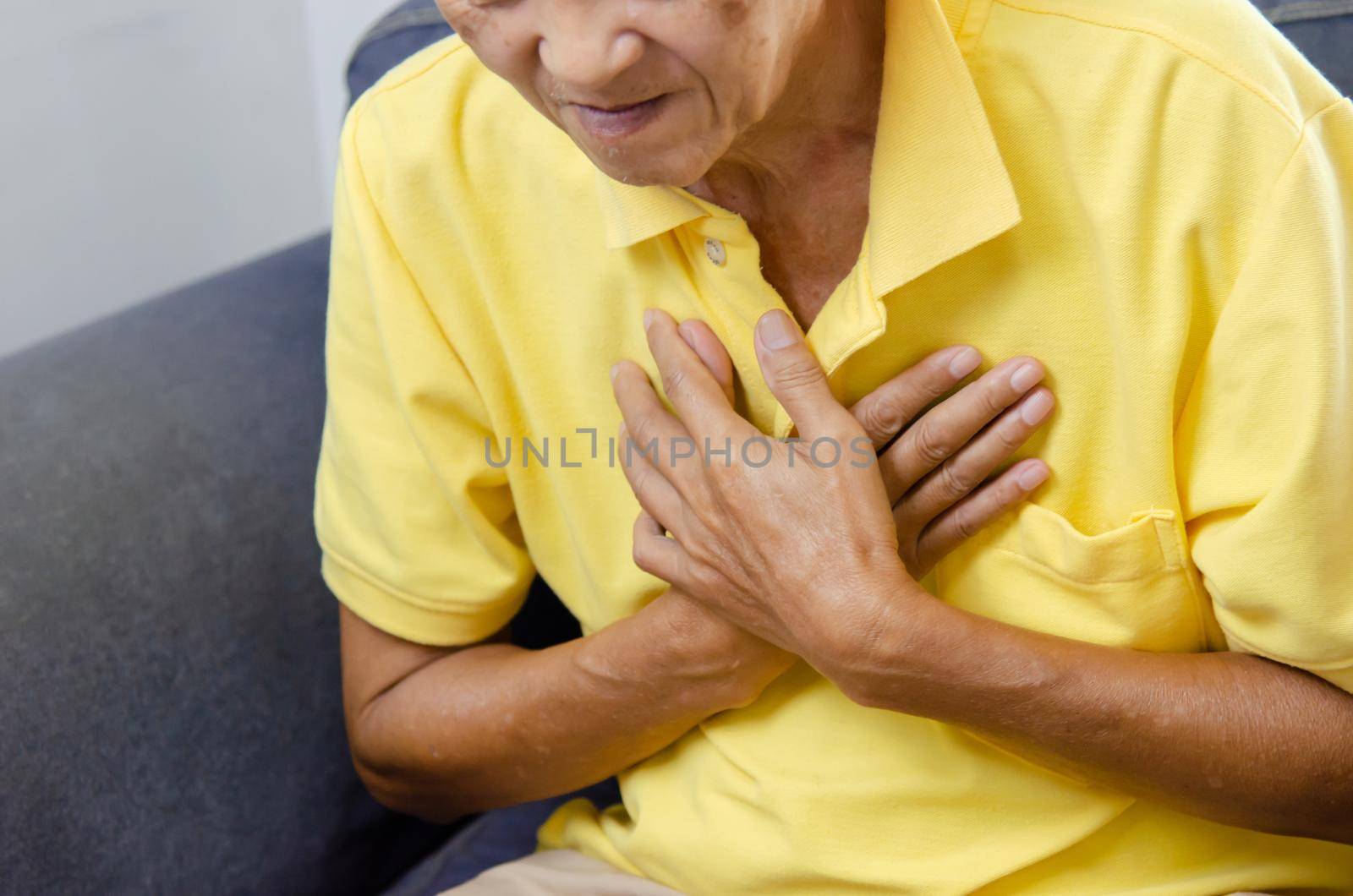 Asian elderly man has chest pain on the sofa.