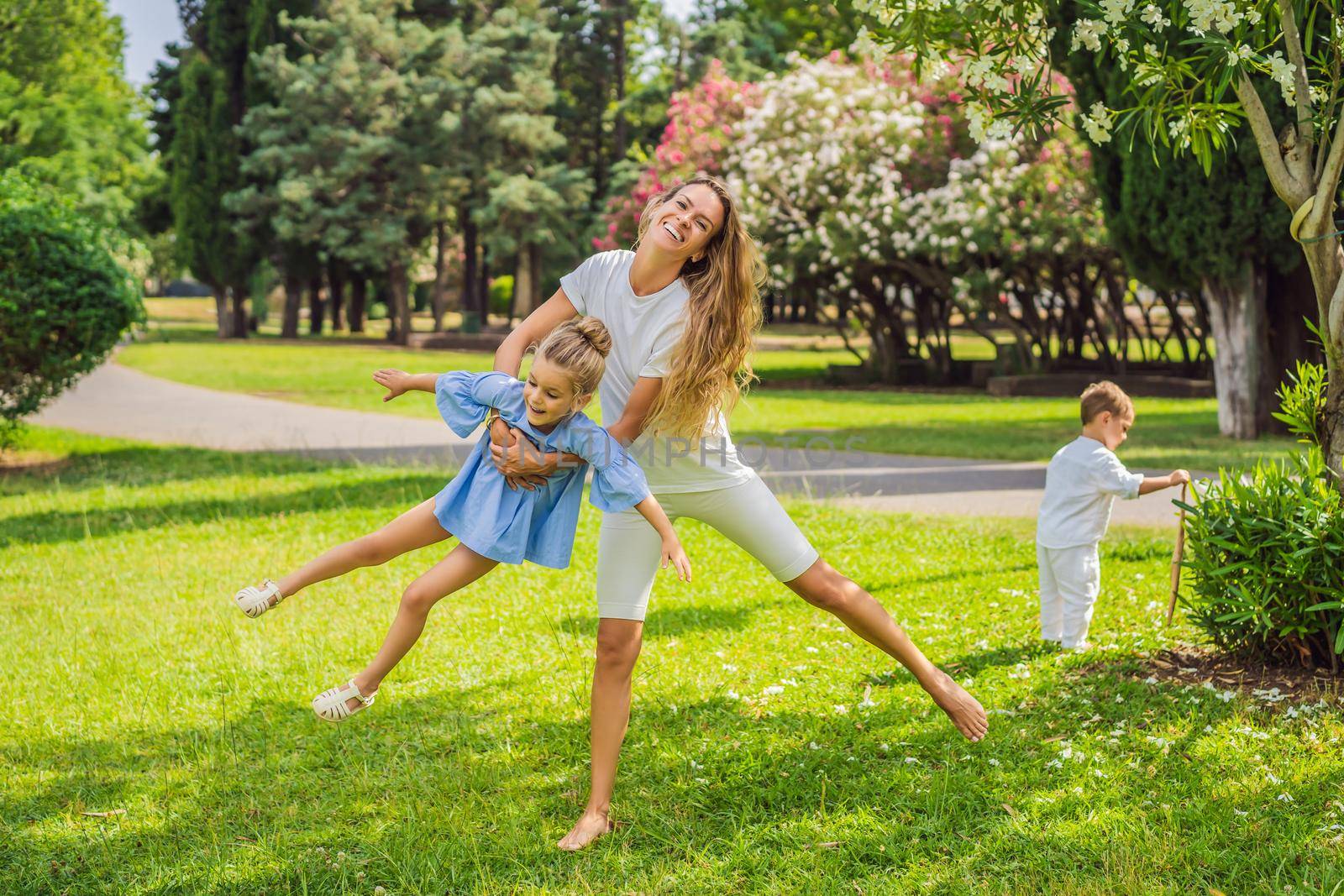 Happy family outdoors on the grass in a park, smiling faces, having fun by galitskaya