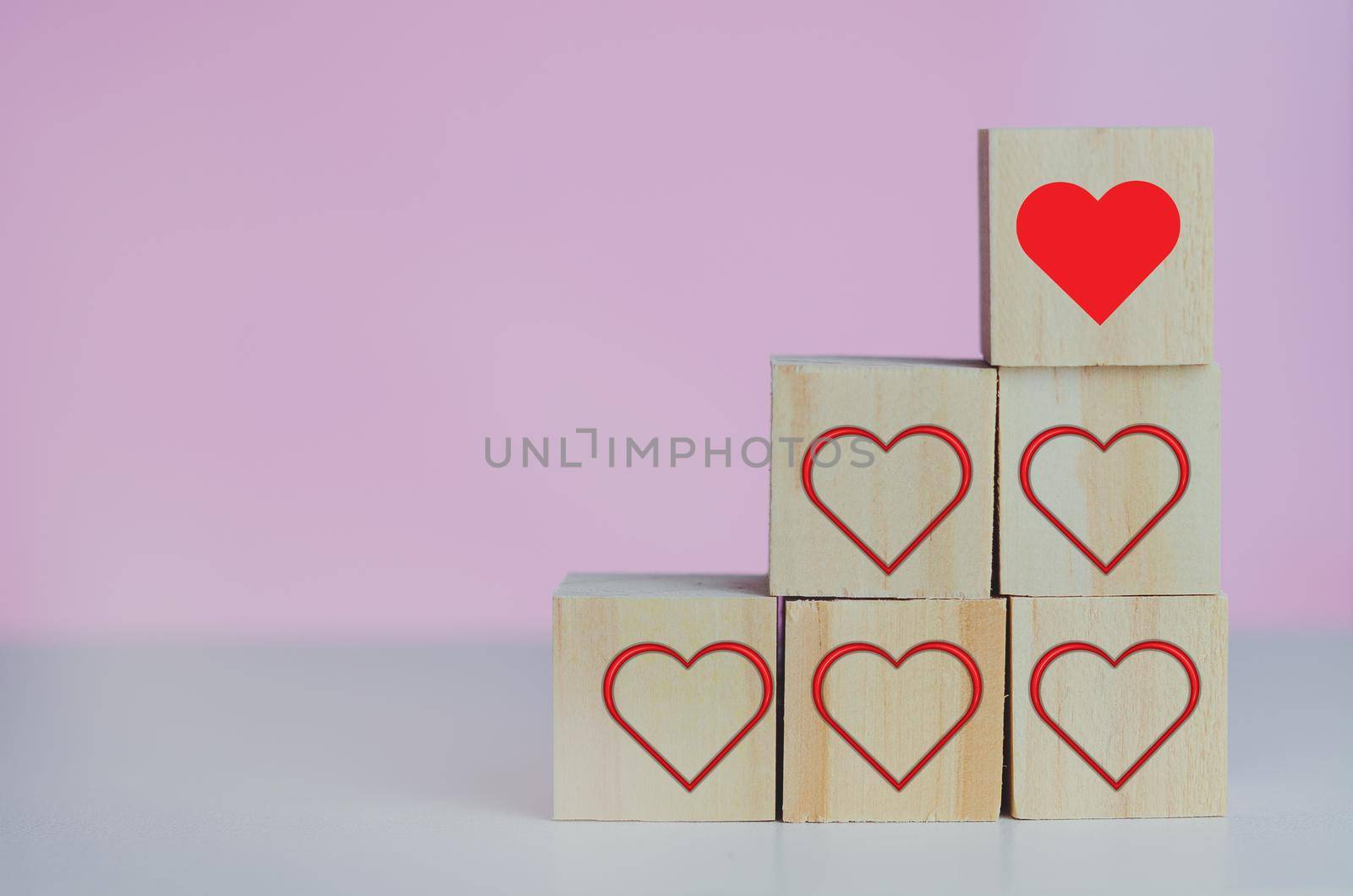 Wooden cubes with love  symbol heart red on the pink background and copy space.