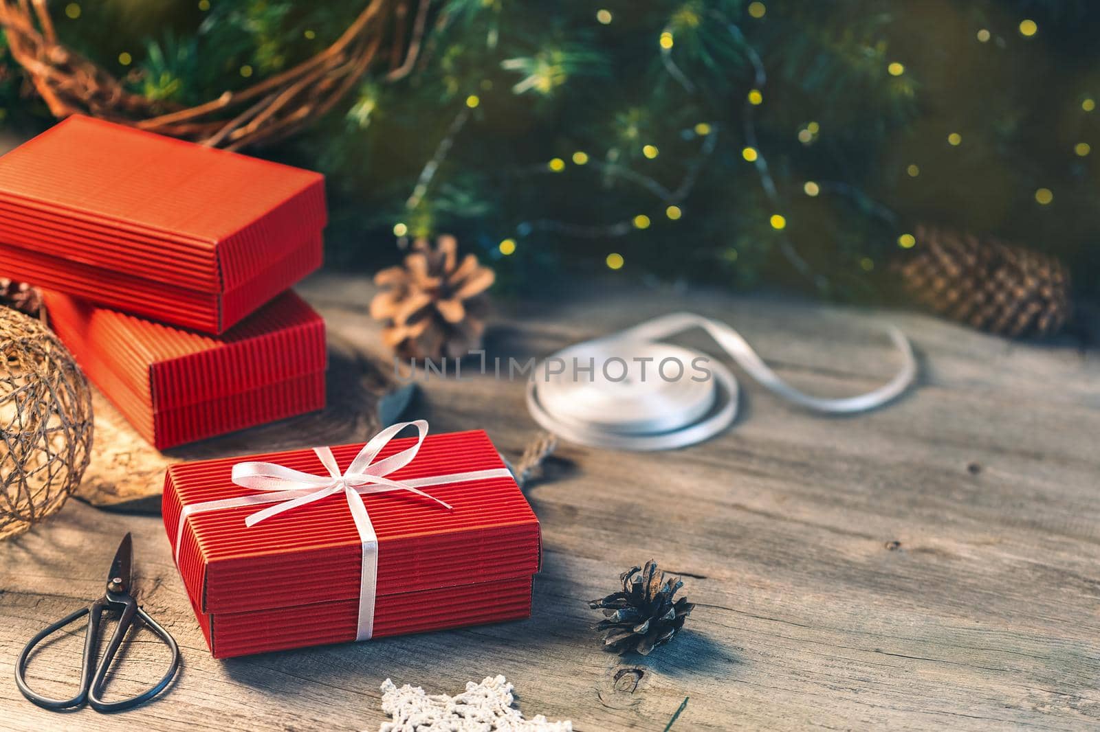Christmas presents preparation, wrapping a red gift box with white ribbon on the wooden table with copy space