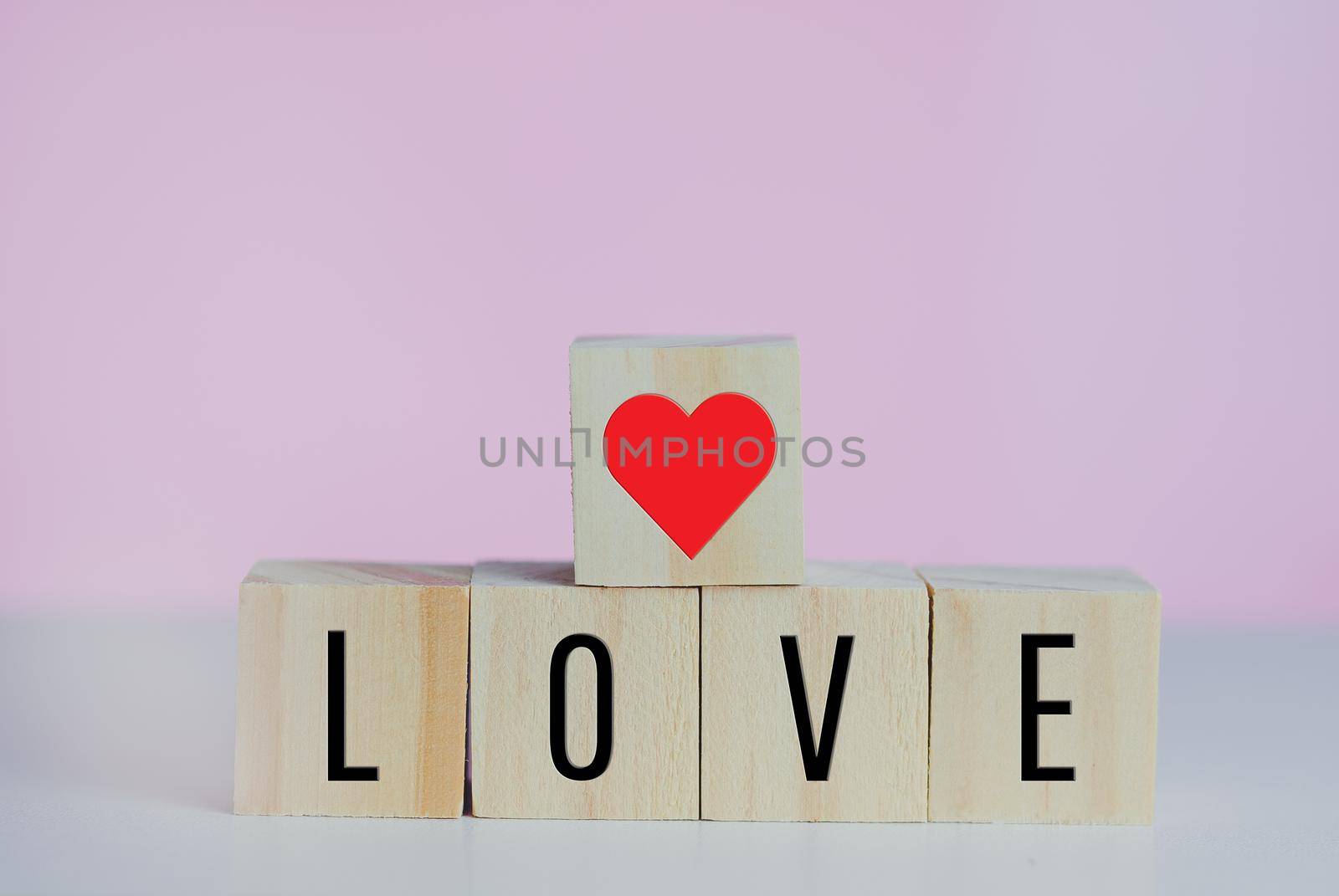 Wooden cubes with love  symbol heart on the pink background and copy space.