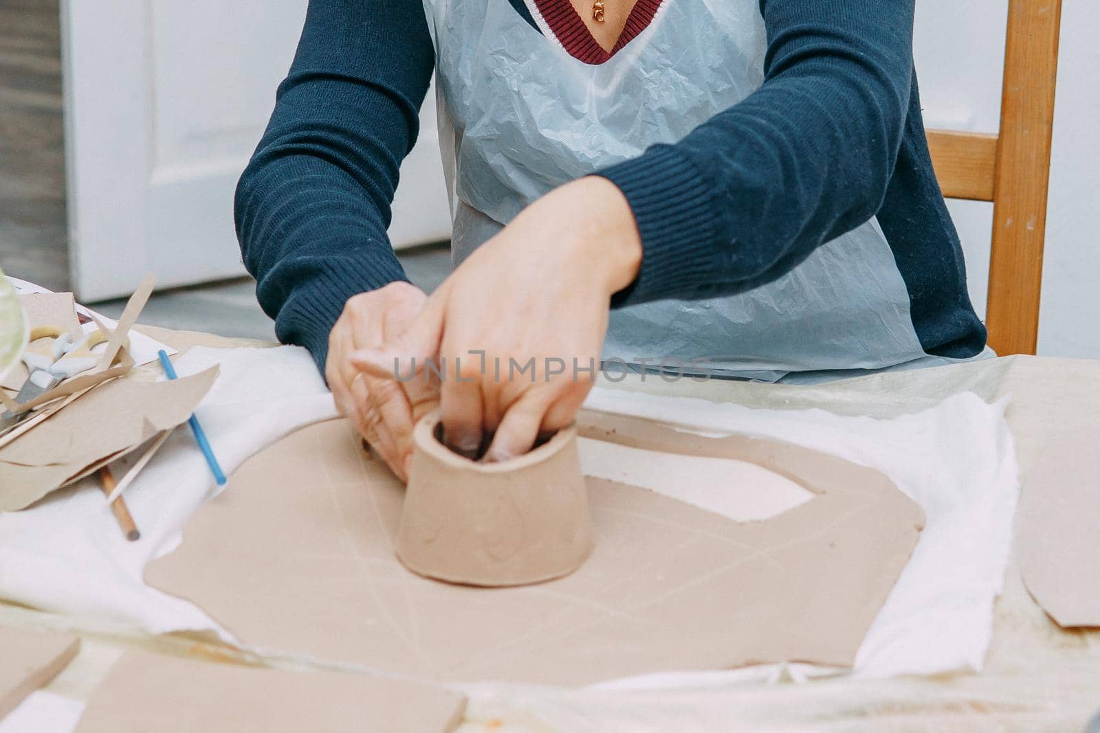 Women's hands knead clay, drawing elements of the product. Production of ceramic products at the master class on ceramics. Close-up.