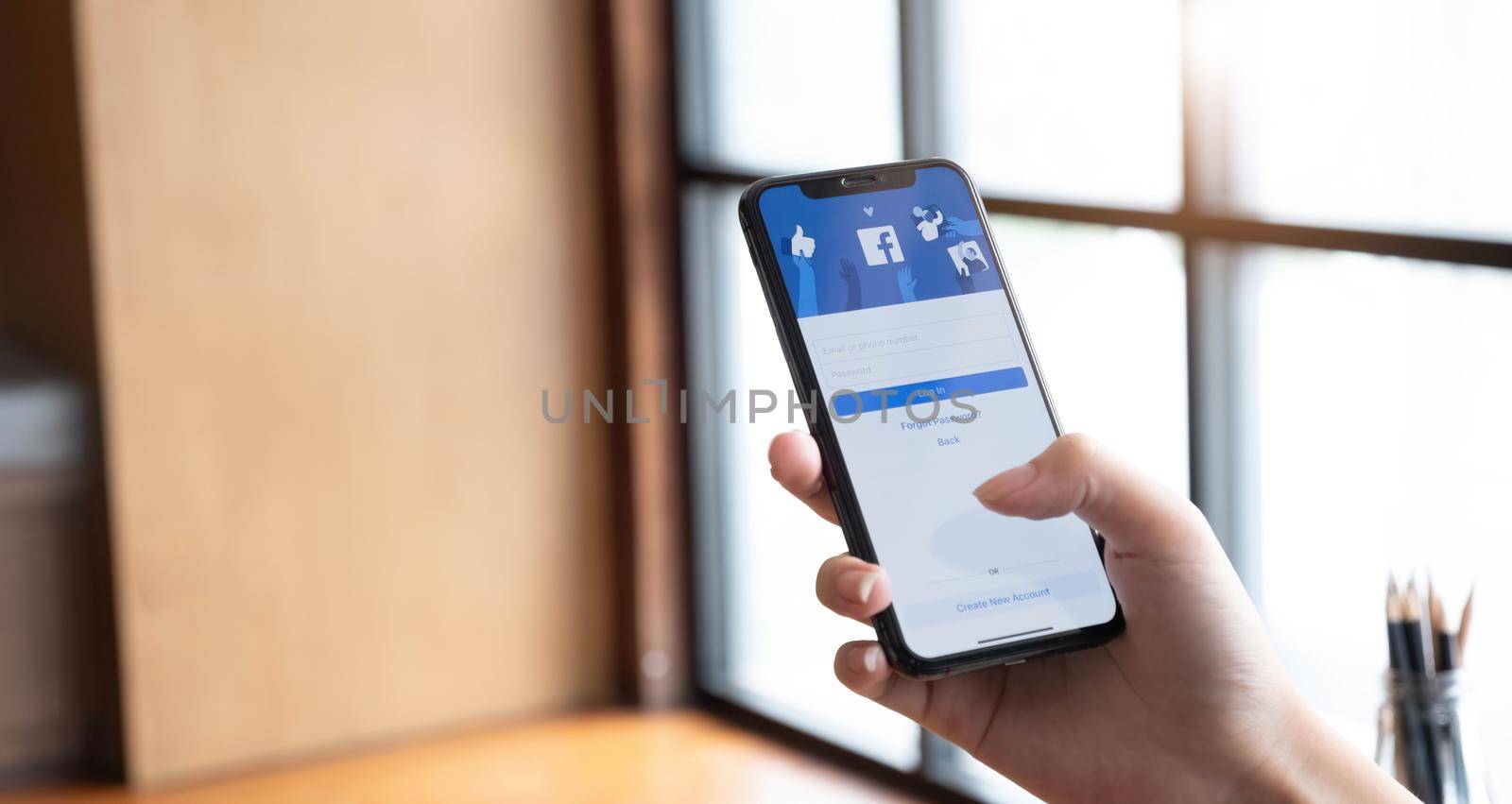 CHIANG MAI ,THAILAND JUL 10 2022 : Woman holding a iPhone X with social Internet service Facebook on the screen. by wichayada