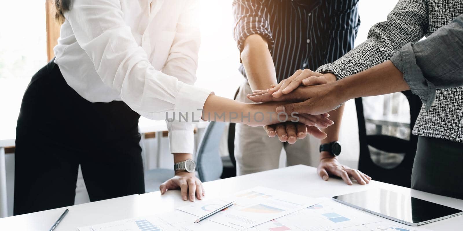 Close up young business people putting their hands together. Stack of hands. Unity and teamwork concept. by wichayada