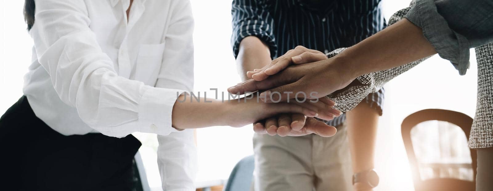 Close up young business people putting their hands together. Stack of hands. Unity and teamwork concept. by wichayada