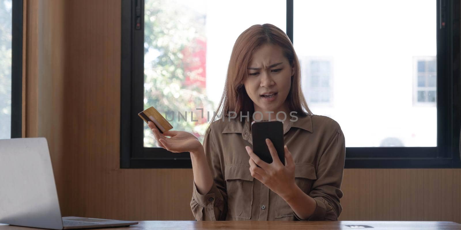 Serious young asian woman complaining her credit card problems with bank's call-centre service. Internet banking problems concept by wichayada