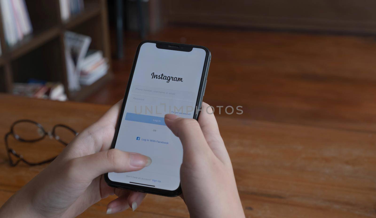 CHIANG MAI, THAILAND - JUL 10, 2022 A woman holds Apple iPhone X with Instagram application on the screen at cafe. Instagram is a photo-sharing app for smartphones..