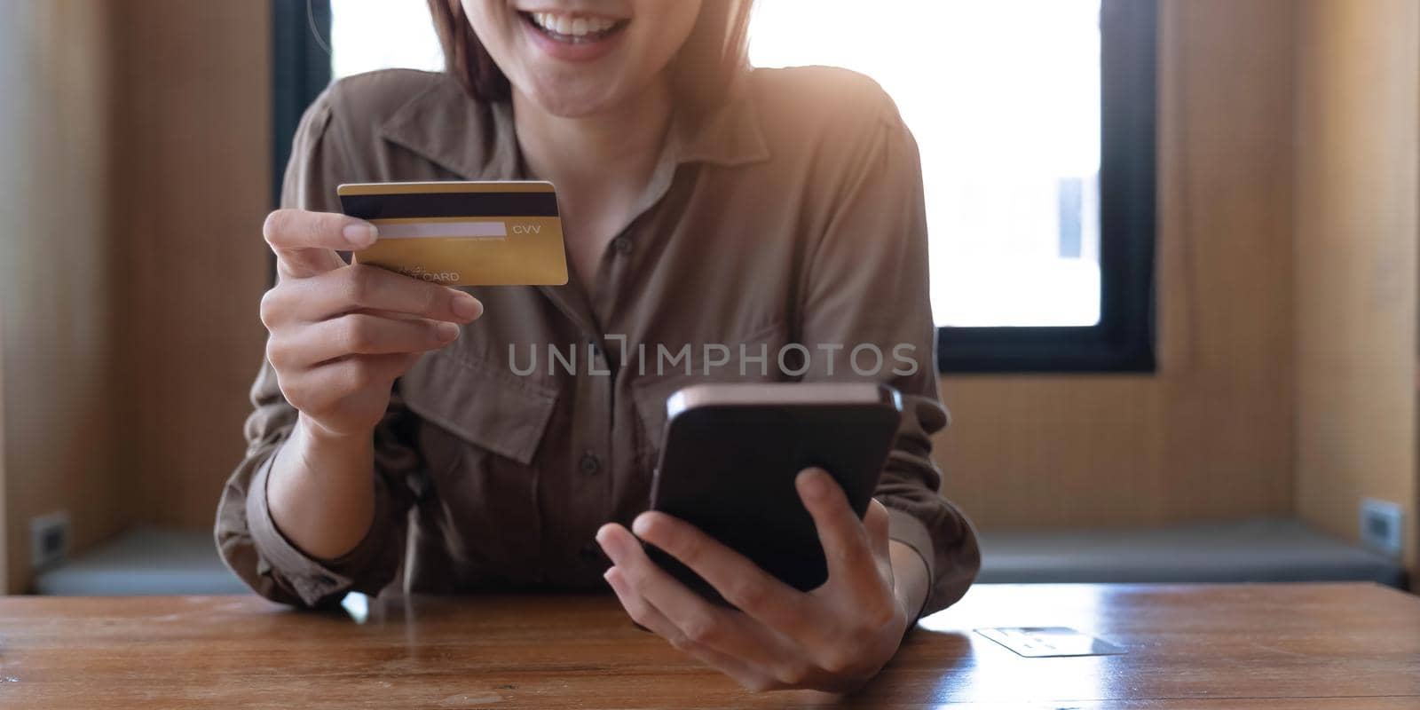 Closeup woman's hands holding a credit card and using smartphone for online shopping..