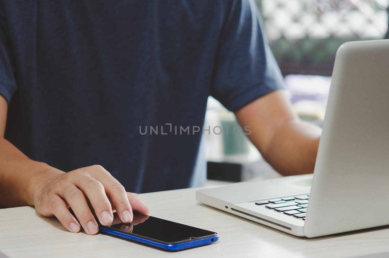 man working at computer desk pressing mobile phone