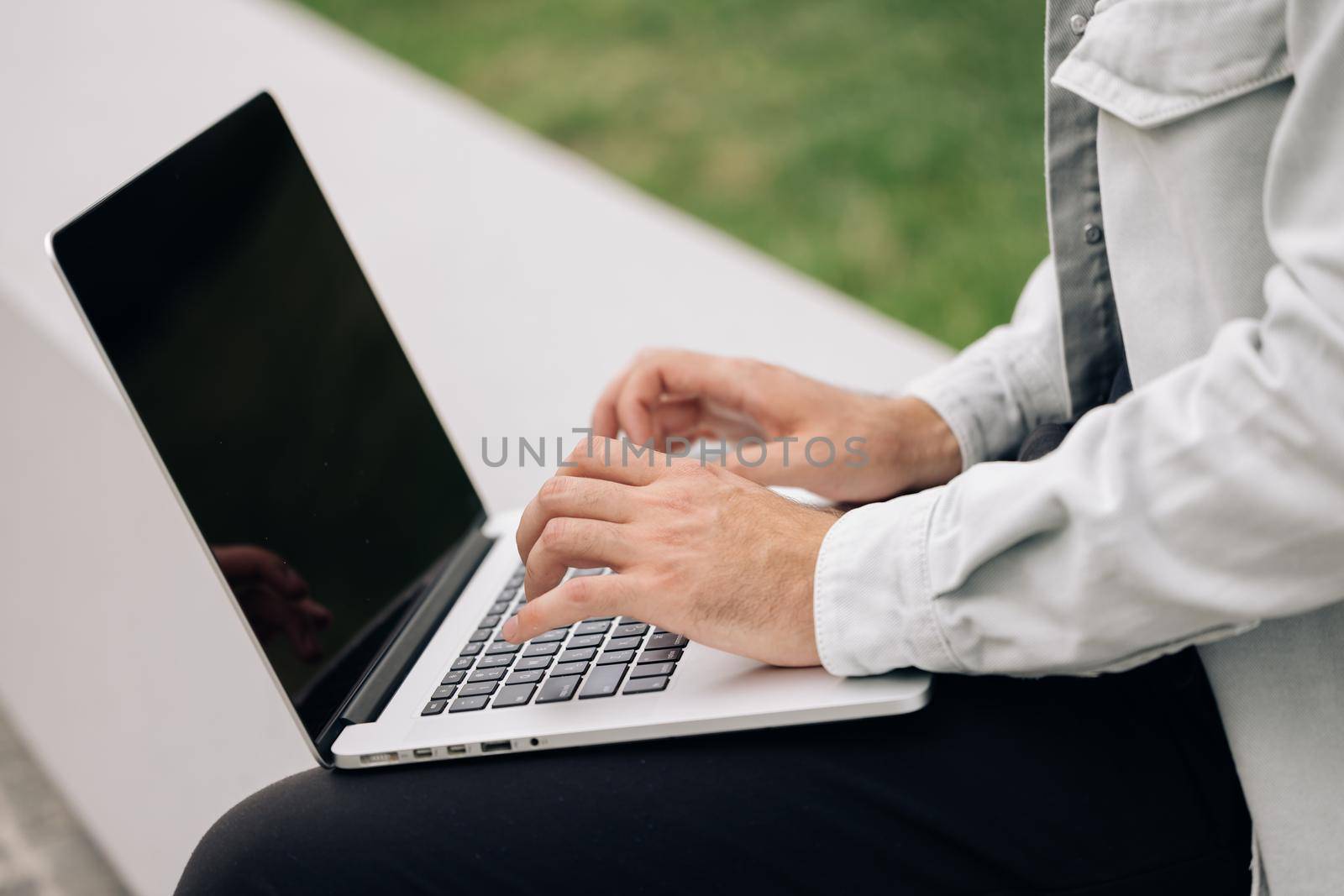 Male user hands typing on laptop keyboard sit on bench, mixed race ethnic businessman hipster student professional study work with pc software technology concept. Freelancer working on laptop.