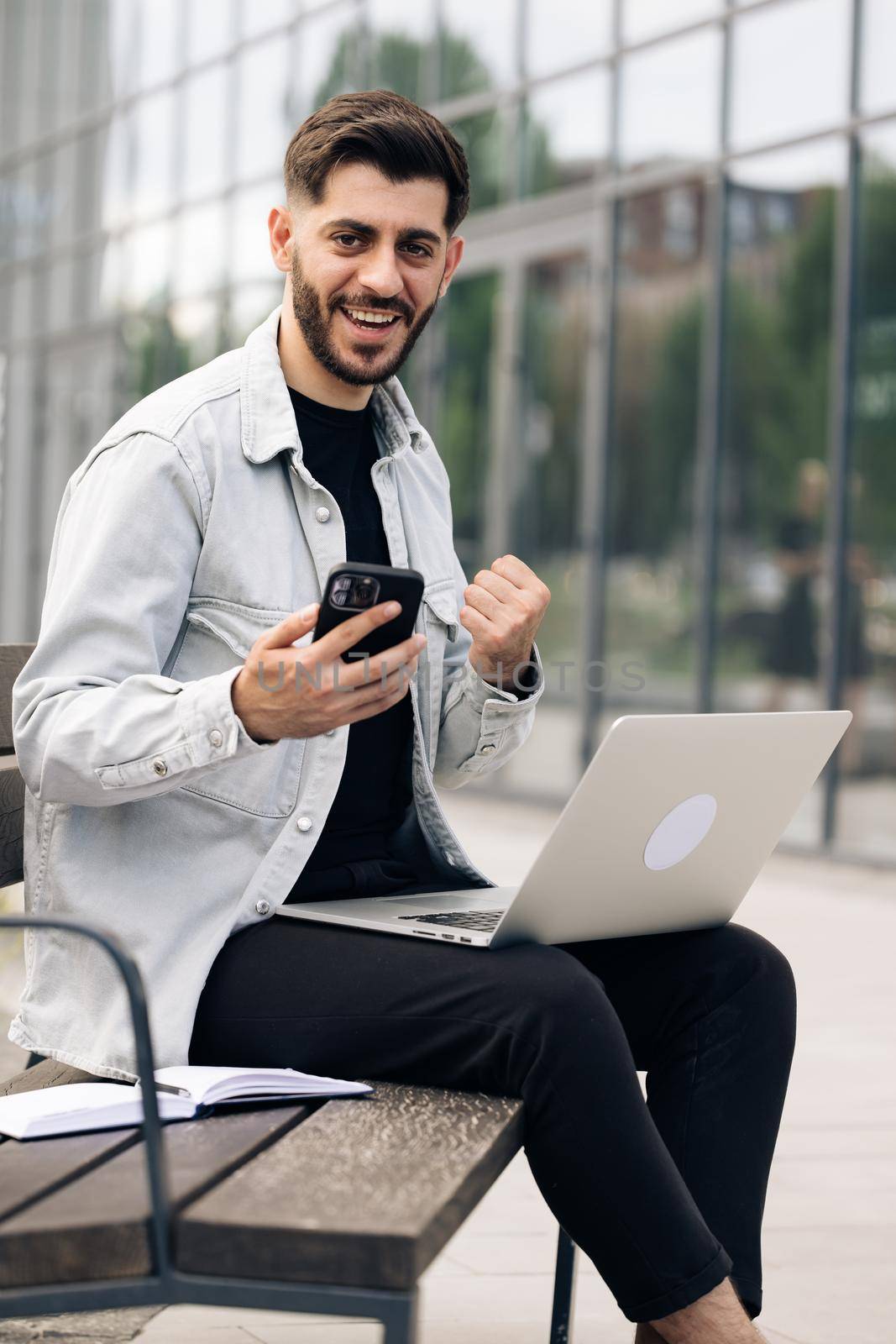 Vertical orientation of happy business man enjoy success on mobile phone. Joyful guy reading good news on smartphone. Surprised male celebrating victory on smart phone by uflypro