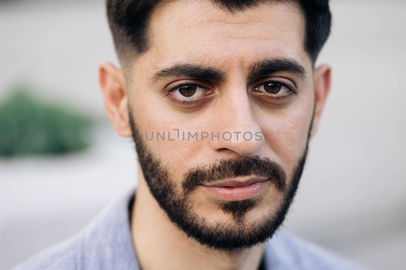 Face of serious bearded caucasian armenian young man looking at camera. Attractive guy stand on street city lifestyle. People. Beauty. Stand outdoors.
