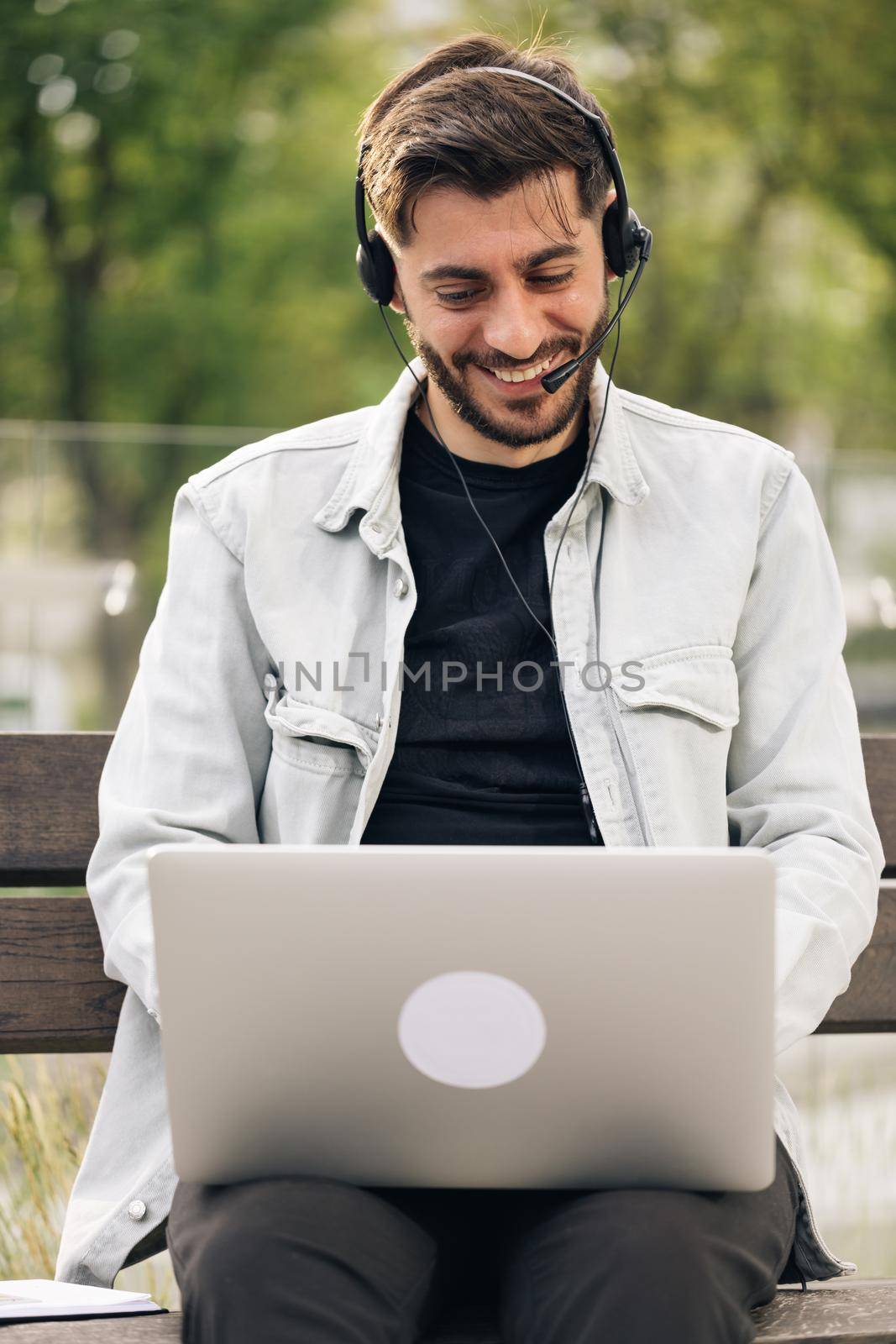 Ethnic businessman speaking looking at laptop computer, online conference distance office chat, virtual training concept. Business man wearing headphones communicating by video call.