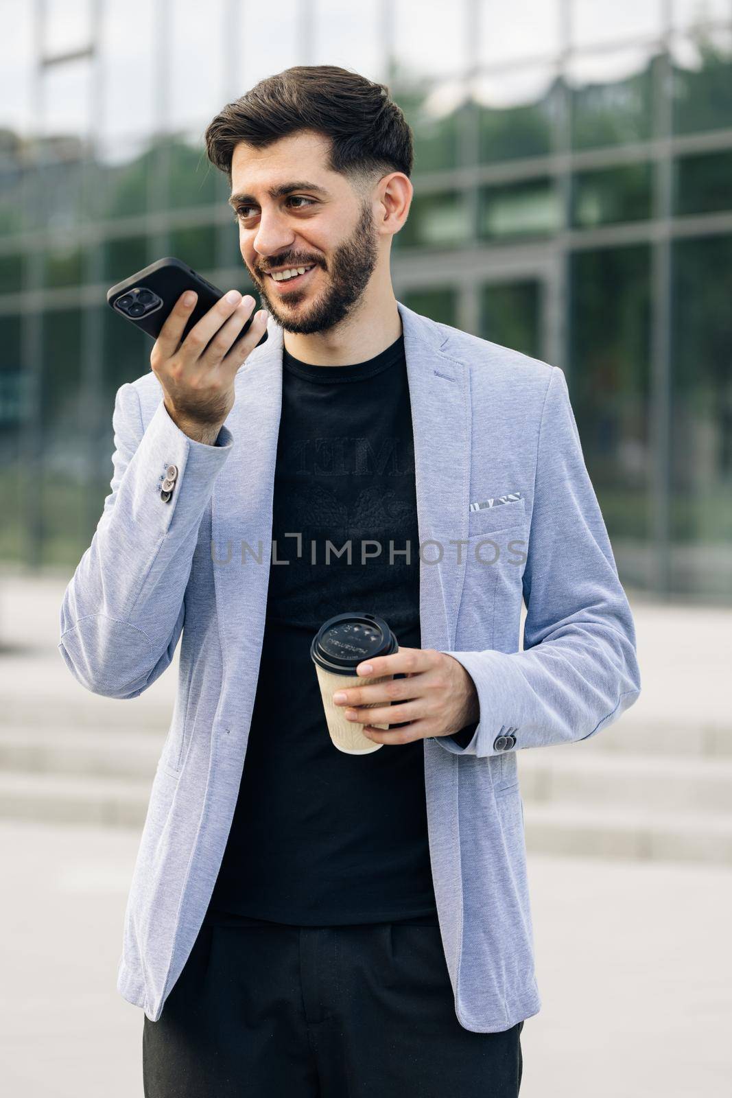 Bearded millennial businessman entrepreneur talk on speakerphone with friend make voice recognition use virtual assistant digital application record audio message on mobile app by uflypro