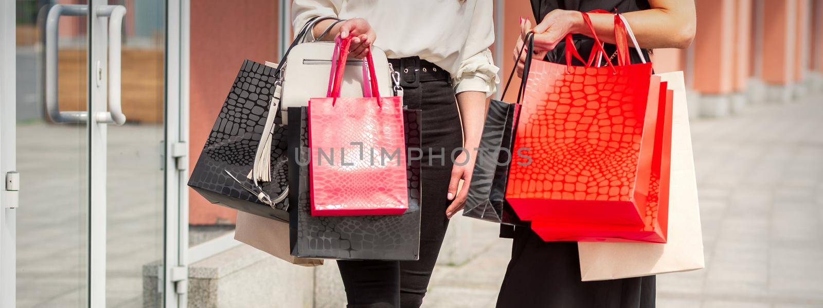 Two young women with shopping bags standing near the shopping mall outdoors